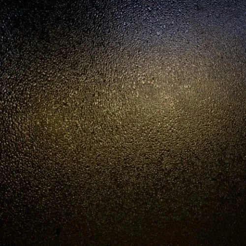 Tummansävyinen pintamateriaali, jossa on pieniä koveria ja kuperia rakenteita.