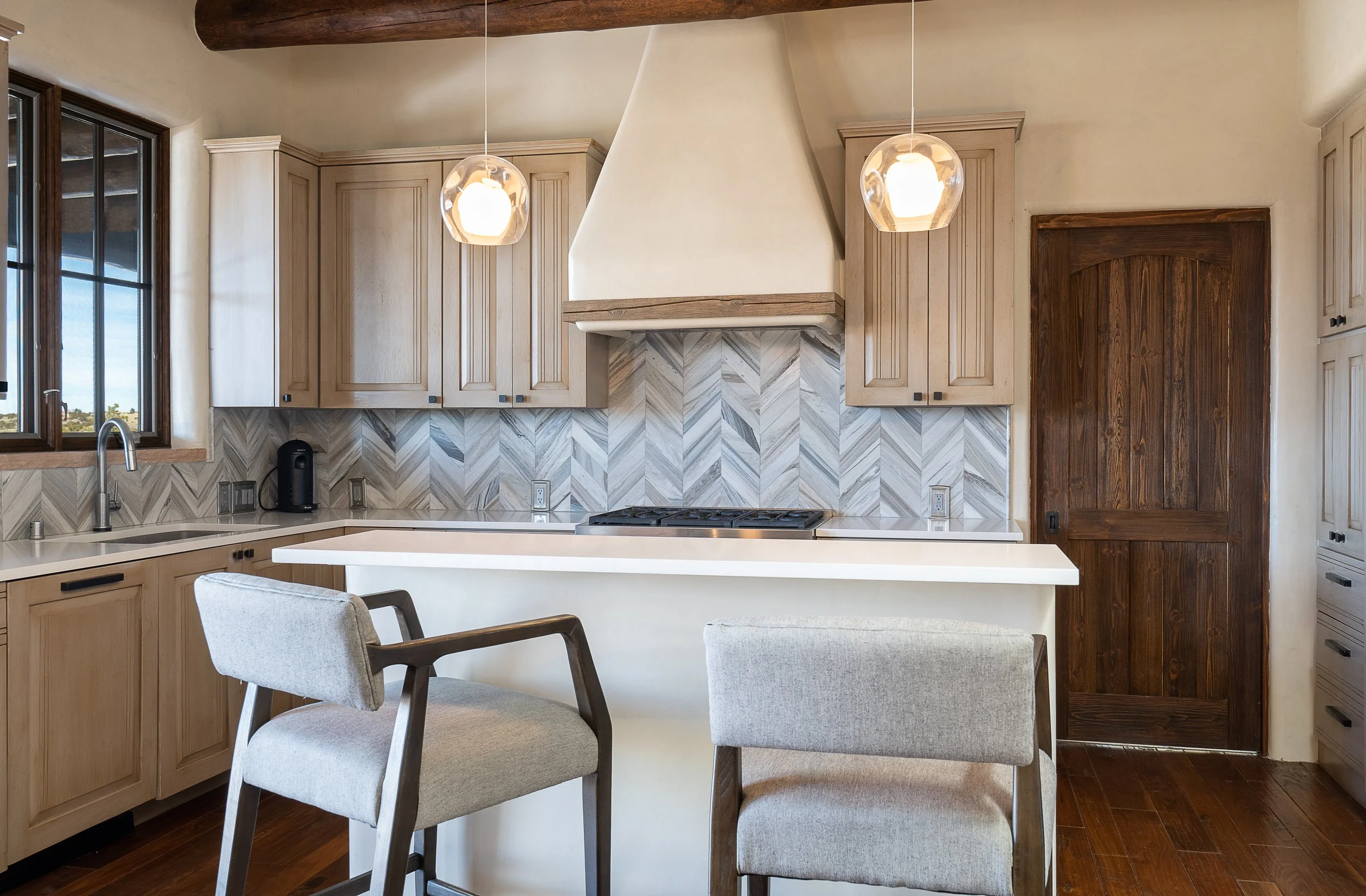 Elegant Kitchen Island with Custom Range Hood and Herringbone Backsplash