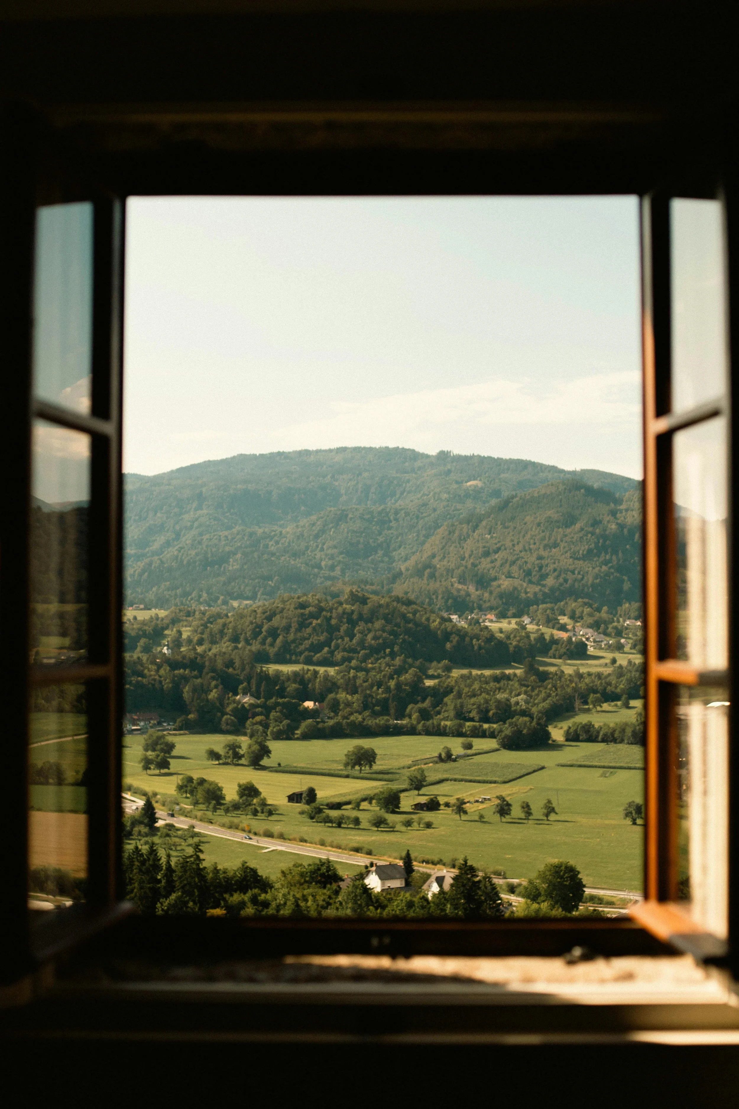 Scenic view of green hills and fields through an open window.