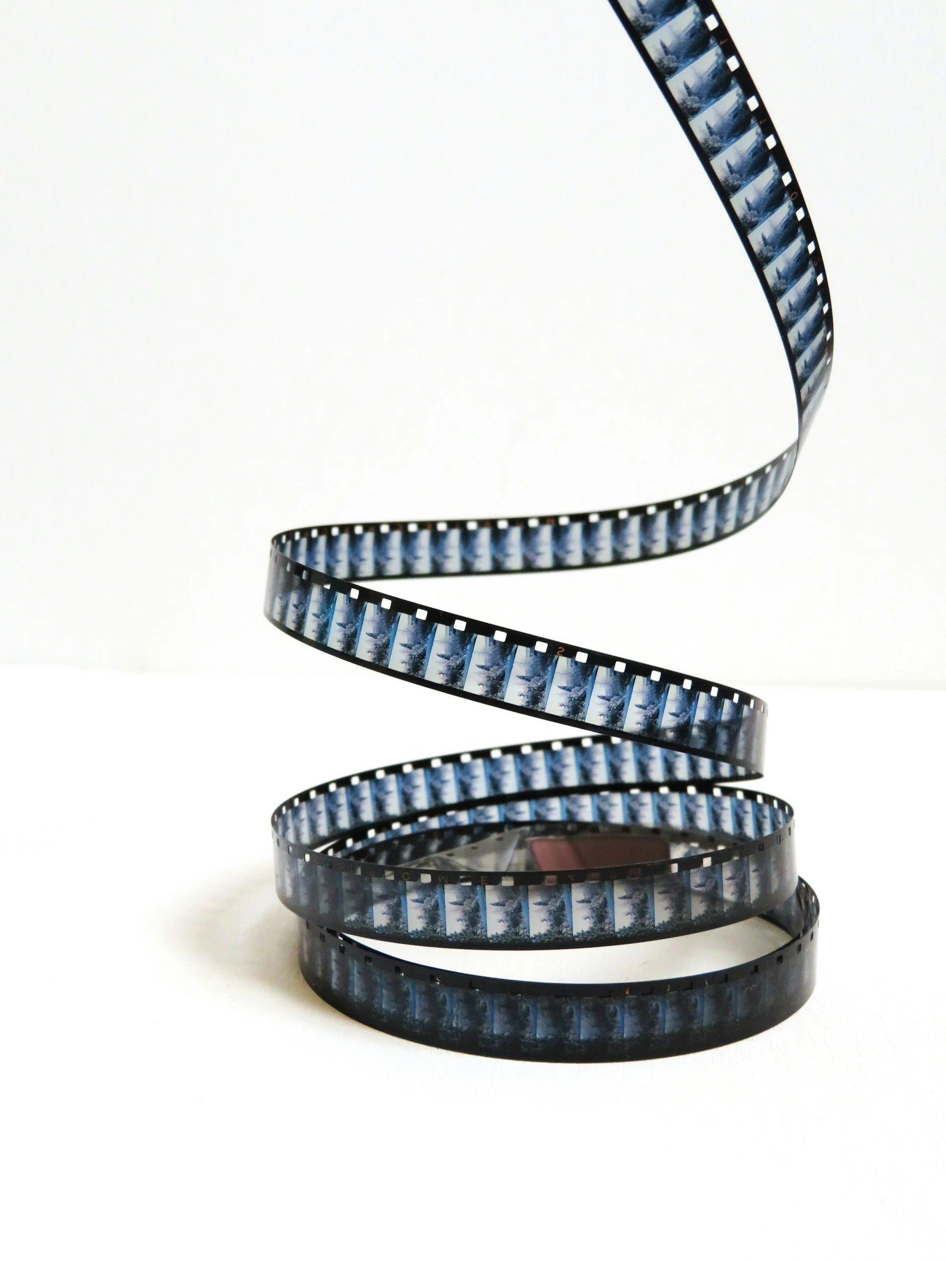 A length of 35mm film strip curled in a spiral on a white background.