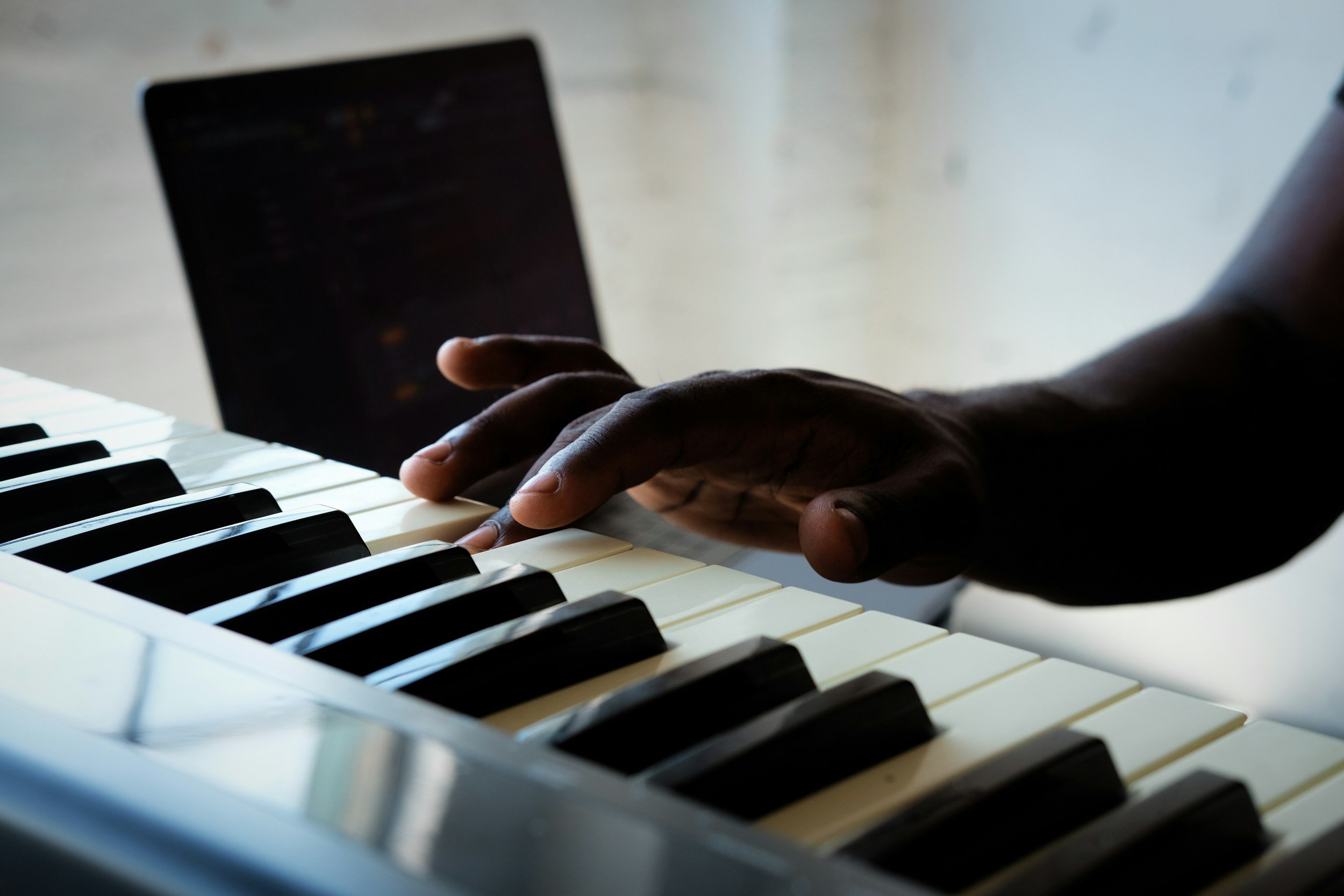 Close-up of a person's hand playing a piano with black and white keys.