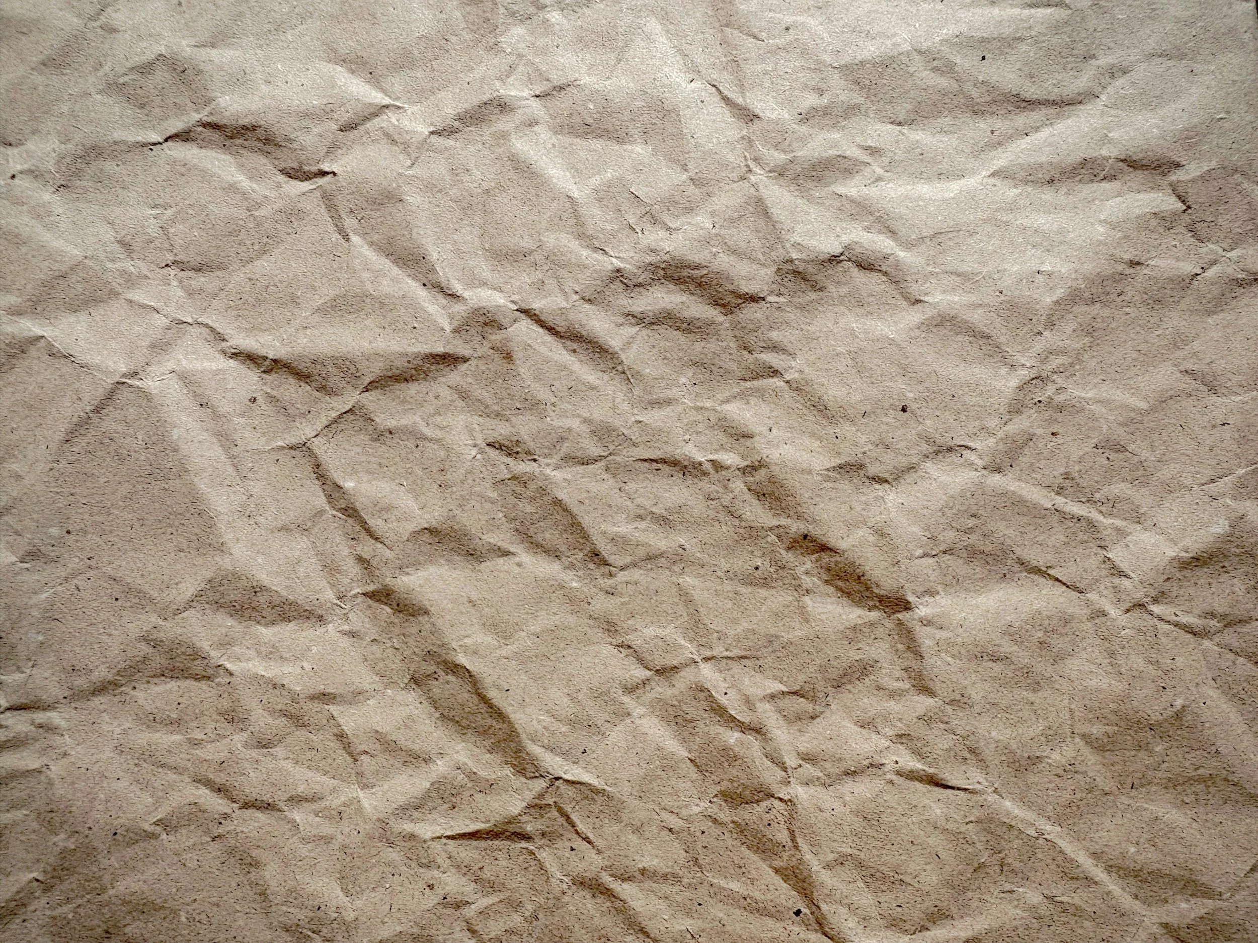 Crumpled brown paper bag or sheet of kraft paper with many wrinkles and creases.