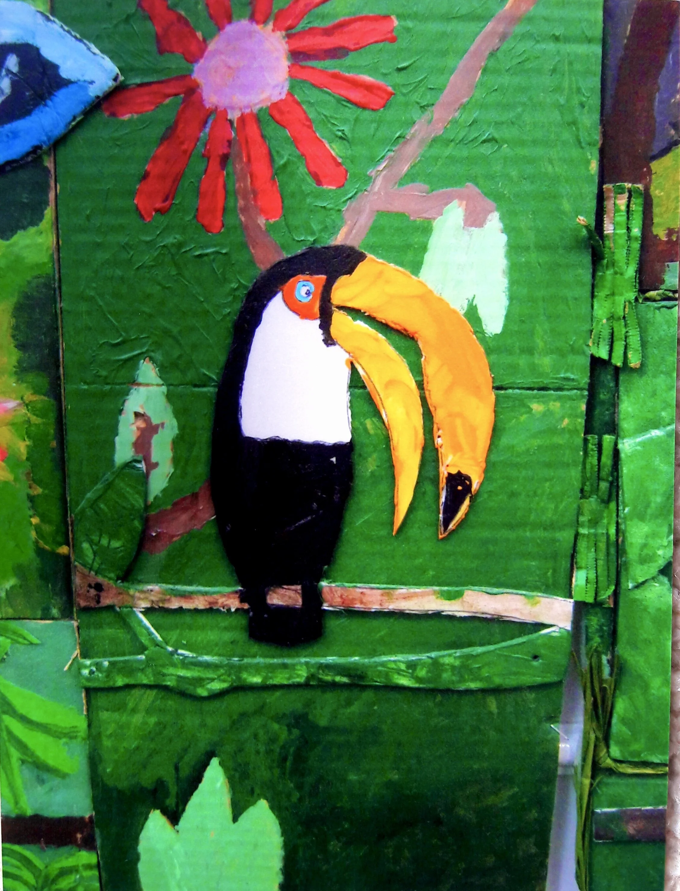 Painted cardboard depicting a toucan with black and white body and large orange beak, set against a background of green leaves and a red flower with a pink center.