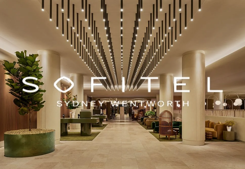 Hotel lobby with modern lighting, large potted plants, and seating areas in Sofitel Sydney Wentworth.