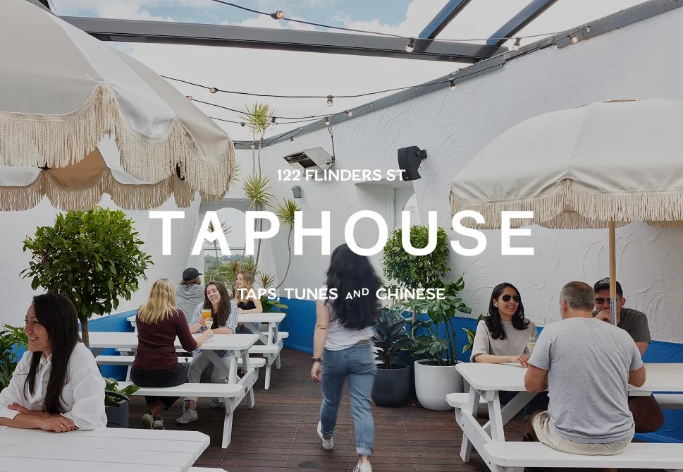 People dining on patio at Taphouse, a restaurant at 122 Flinders Street, with umbrellas and potted plants.