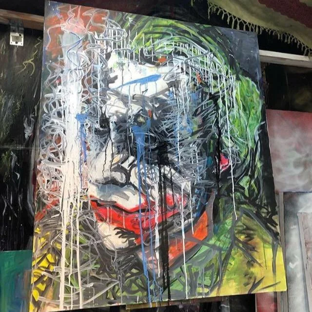 Abstract graffiti-style artwork of a face with glasses, curly hair, and bright red lips, featuring vibrant colors and paint drips.