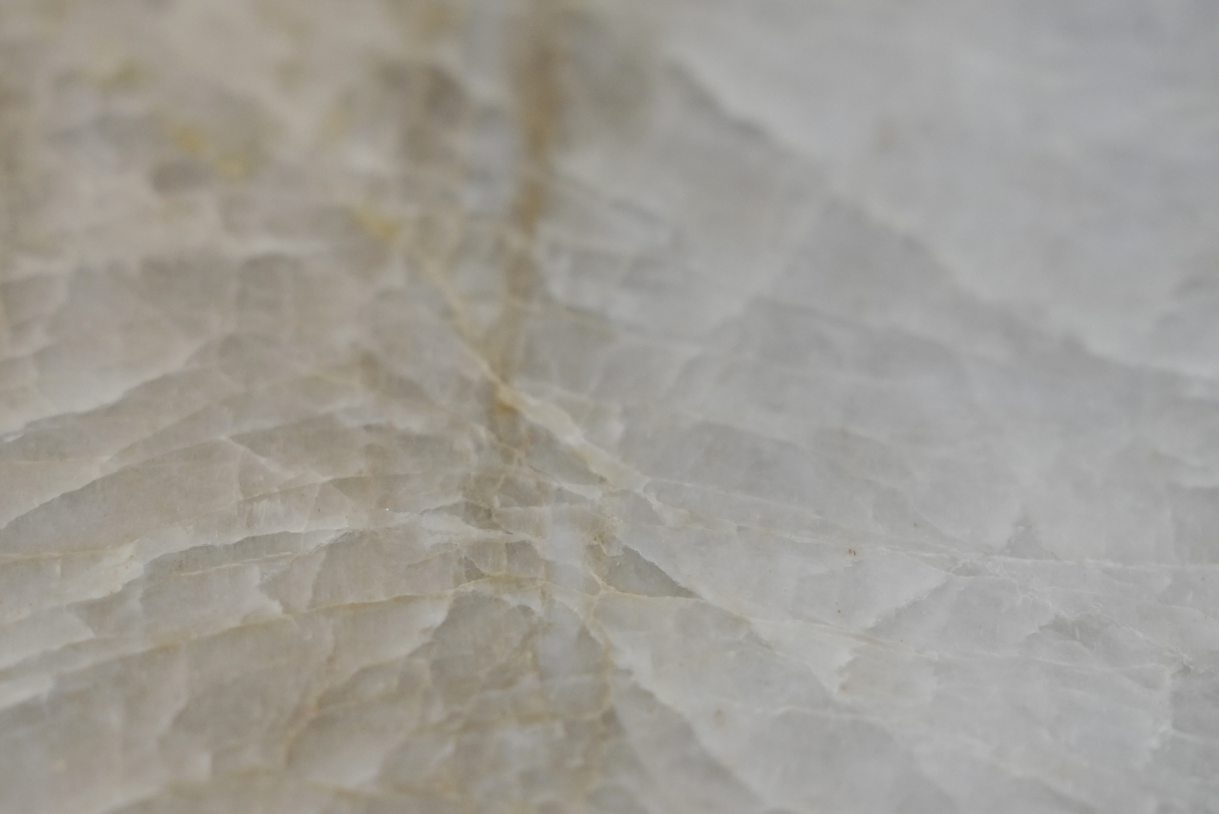 Nahaufnahme von hellgrauem Marmor mit weißlichen und beige Schattierungen, sichtbare Maserung und Textur.
