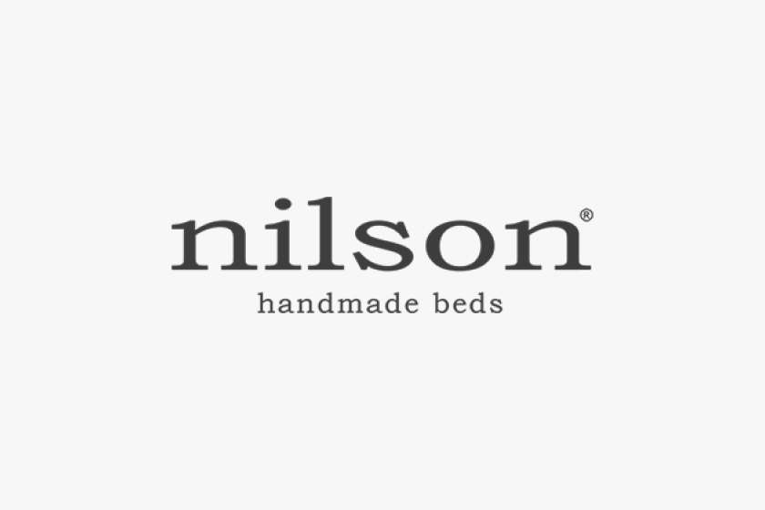 Logo mit dem Text 'nilson' und dem Slogan 'handmade beds' auf grauem Hintergrund.