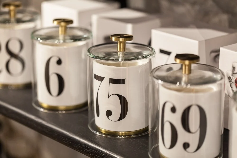 Kleine Kerzen im Glas mit Zahlencover auf einem Regal, die vermutlich einen Adventskalender darstellen.