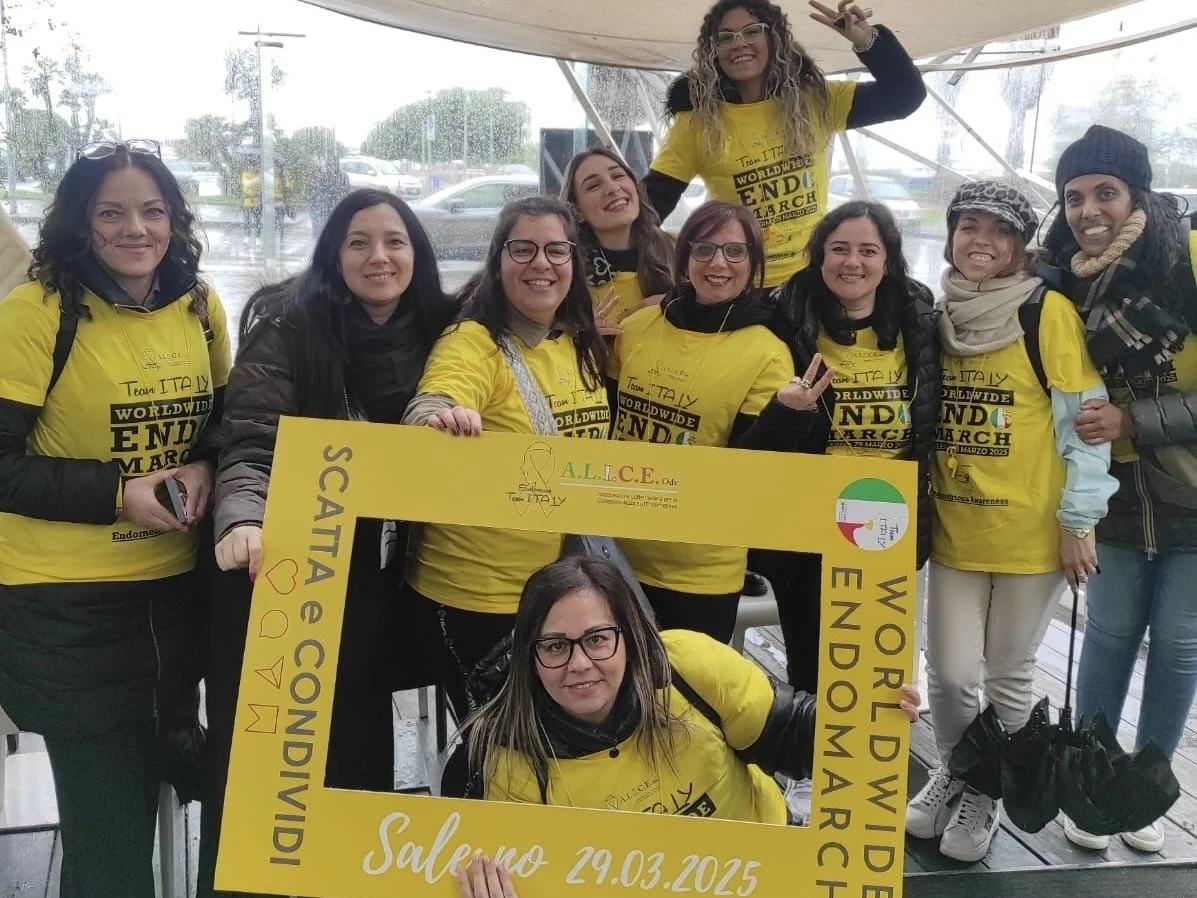Gruppo di donne con magliette gialle che partecipano a un evento di sensibilizzazione, tenendo un cartello con scritto 'Salerno 29.03.2025'.