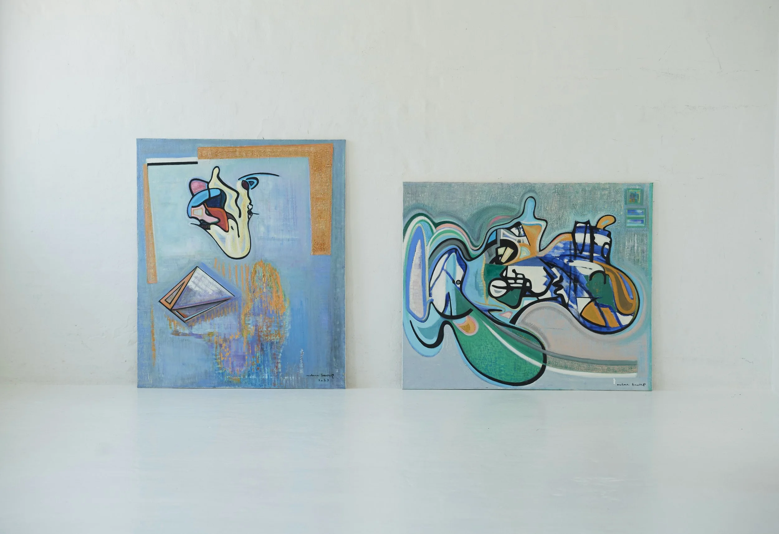 Two abstract paintings on a white wall with a white floor