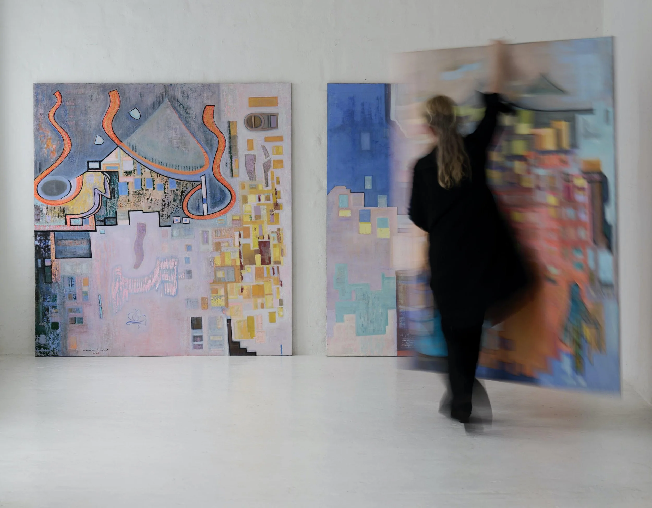 A person in black clothing is moving in front of a wall with multiple colorful abstract paintings, creating a blurred motion effect.