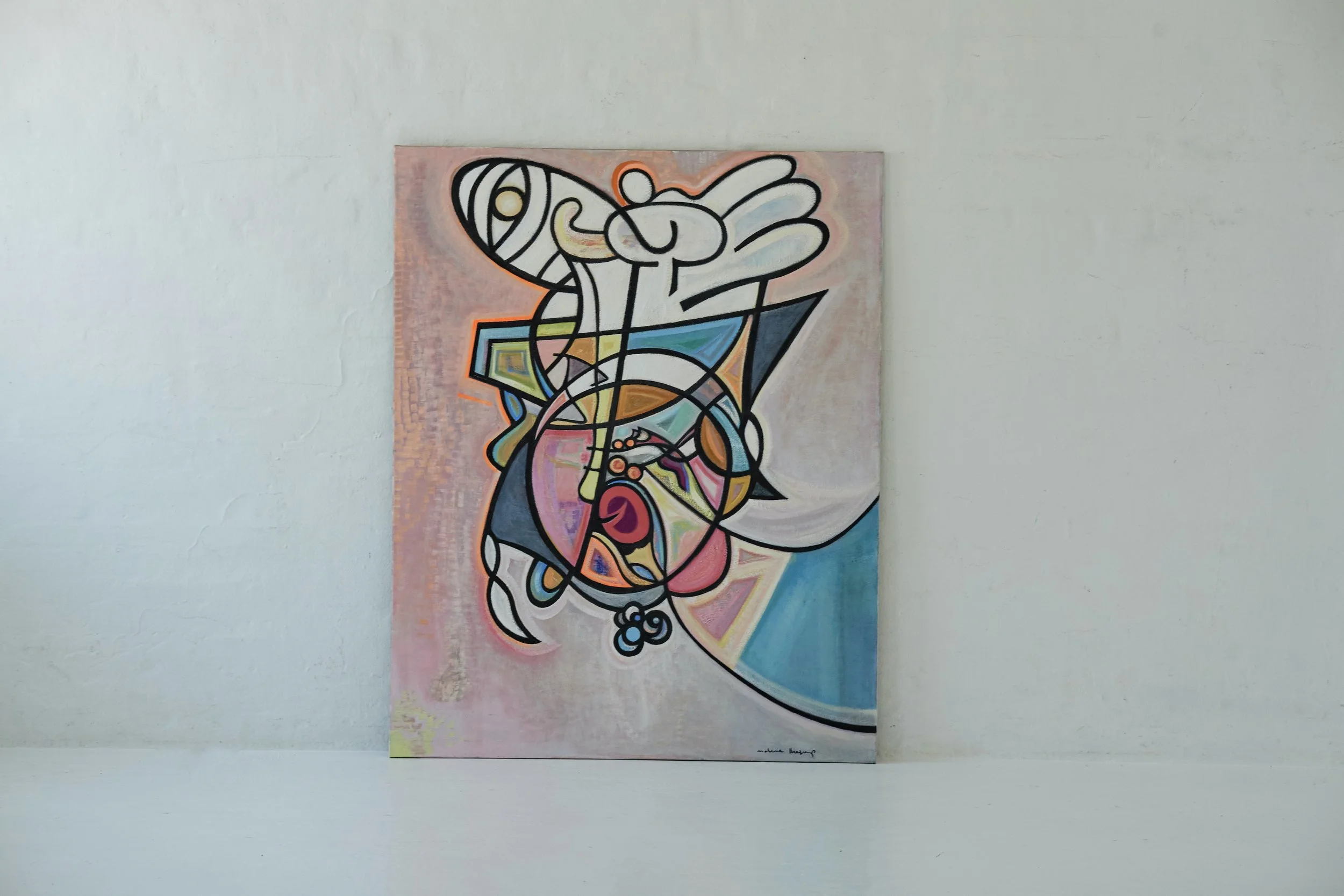 An abstract colorful painting featuring geometric shapes and lines on a canvas, hung on a plain white wall.