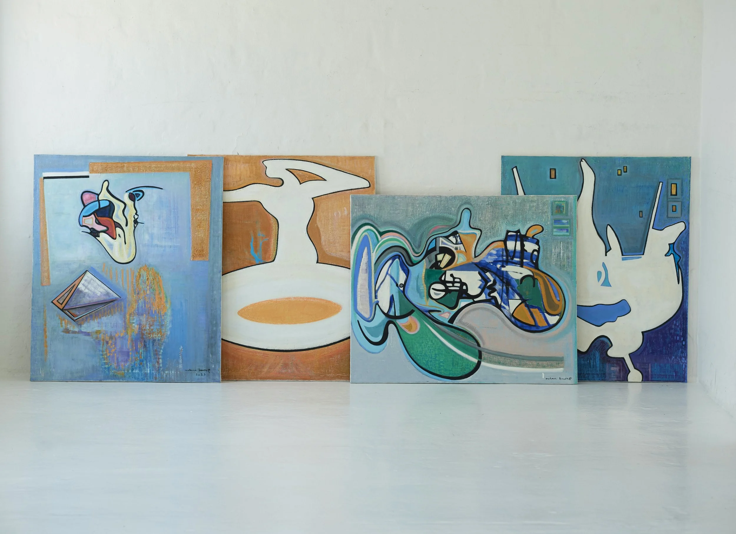 Four abstract paintings lean against a plain white wall in a minimalist gallery setting.