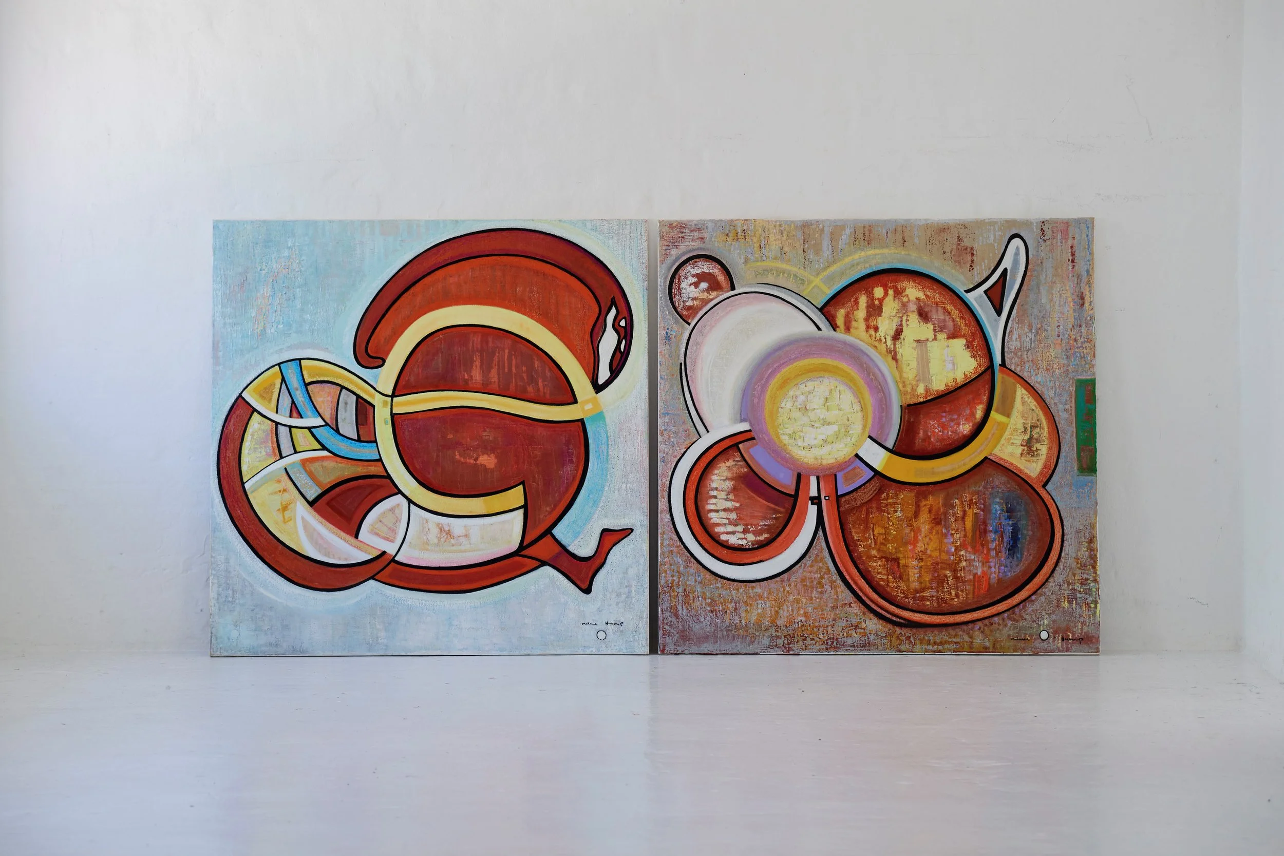 Two abstract paintings with bold colors and geometric shapes on a white gallery wall.