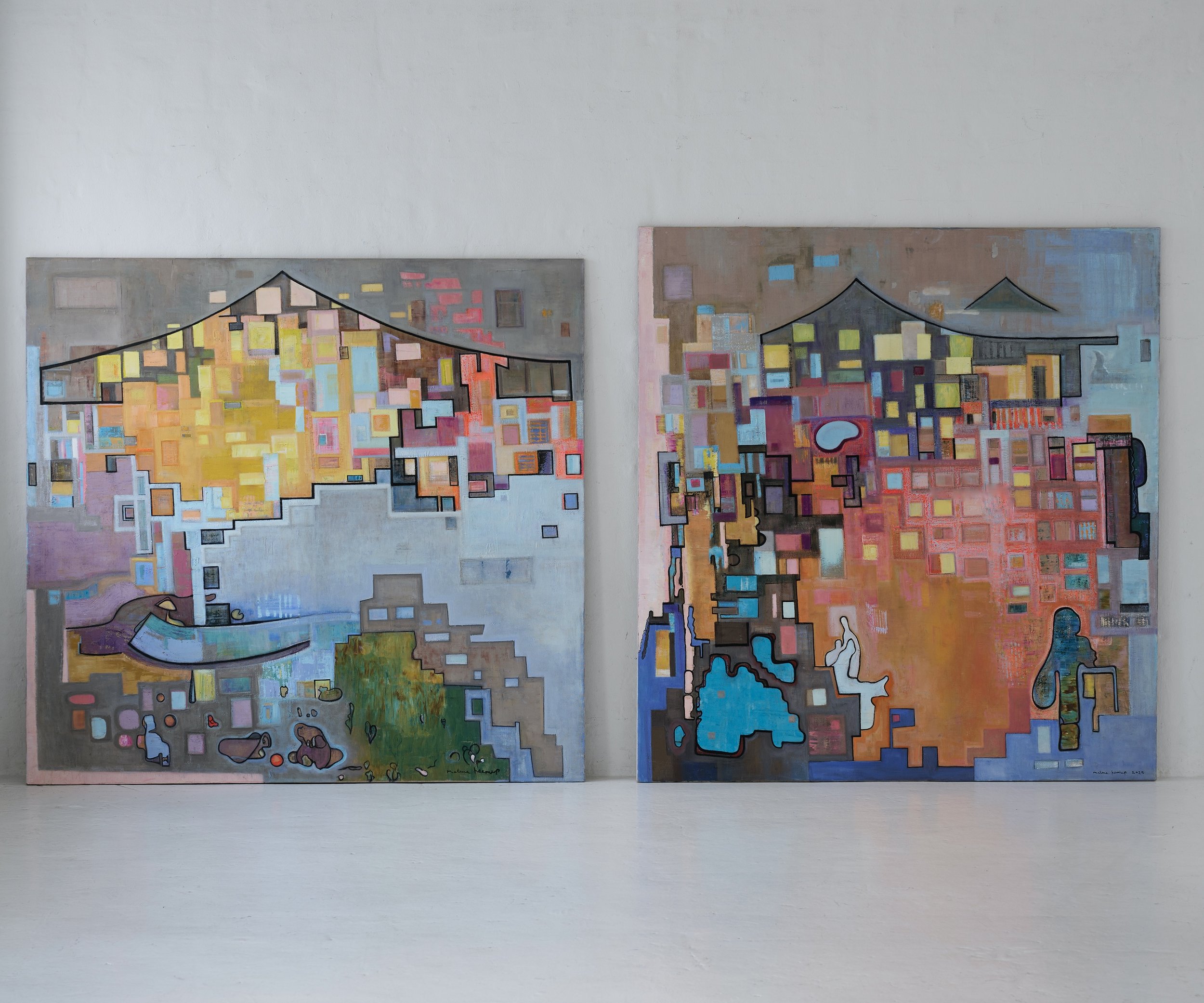 Two abstract paintings on a white wall featuring colorful geometric shapes, with a landscape-like theme including sections resembling buildings and natural elements, framed by black outlines.