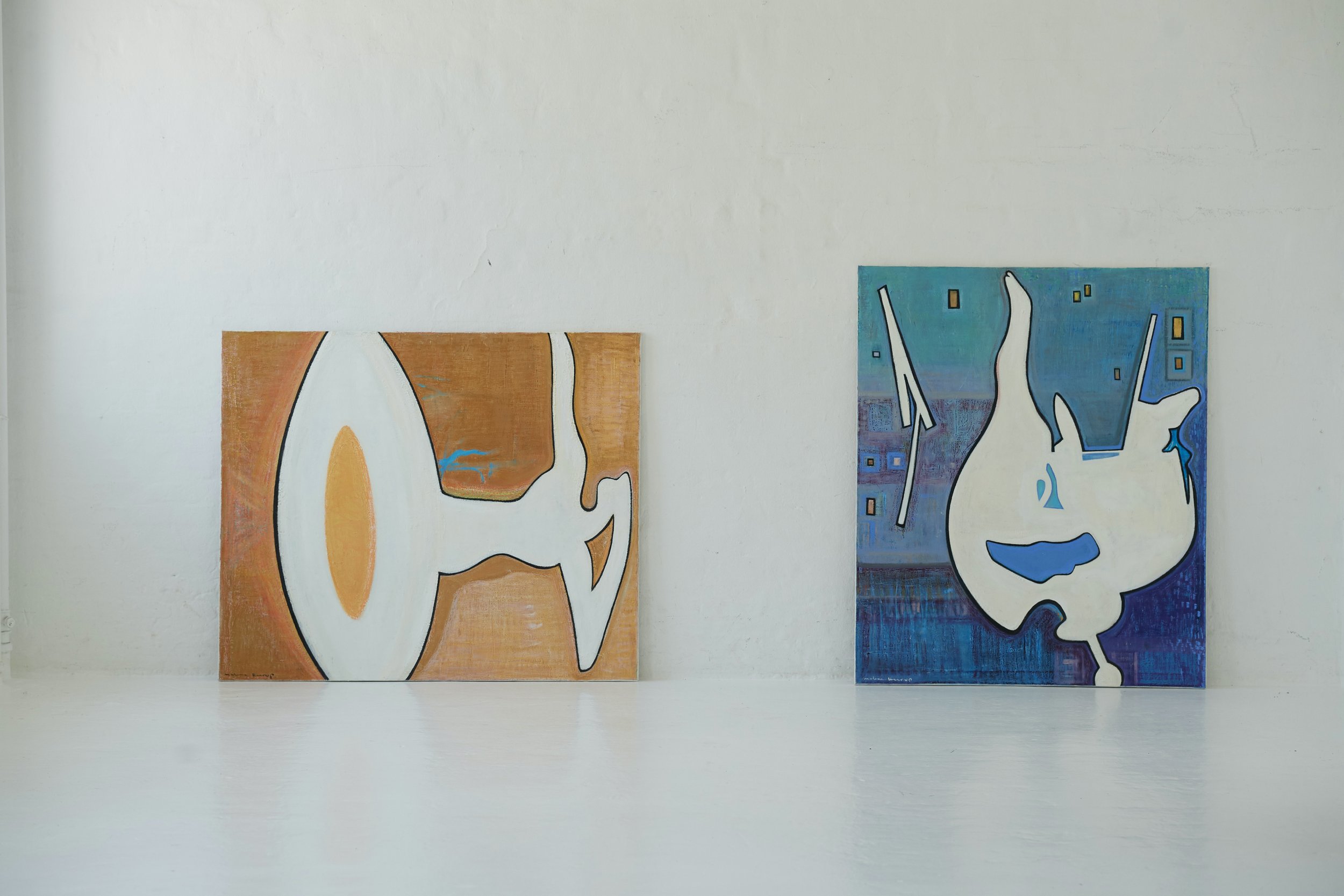 Two abstract paintings on a white gallery wall, with the left painting featuring warm brown tones and white shapes, and the right painting featuring cool blue tones and geometric shapes.
