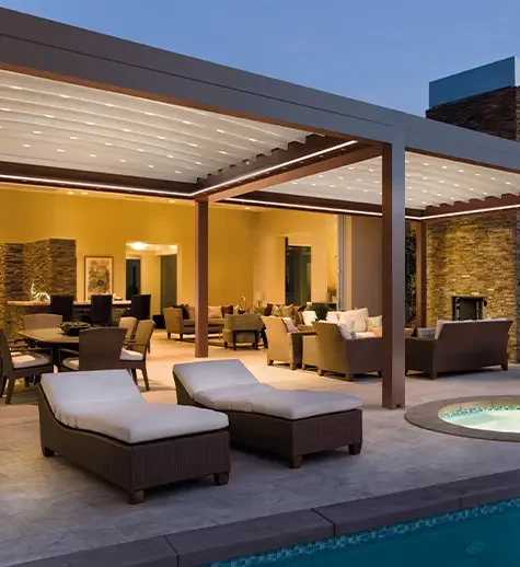 Outdoor patio with lounge chairs, sofas, and a dining area under a pergola, overlooking a swimming pool.