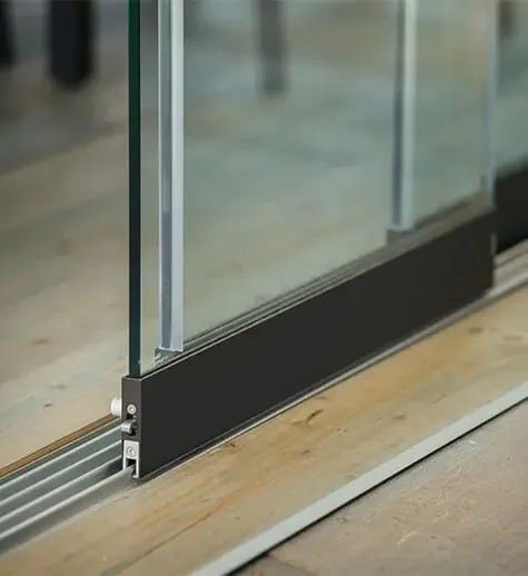 Close-up of glass sliding door track with a glass panel in a modern building.