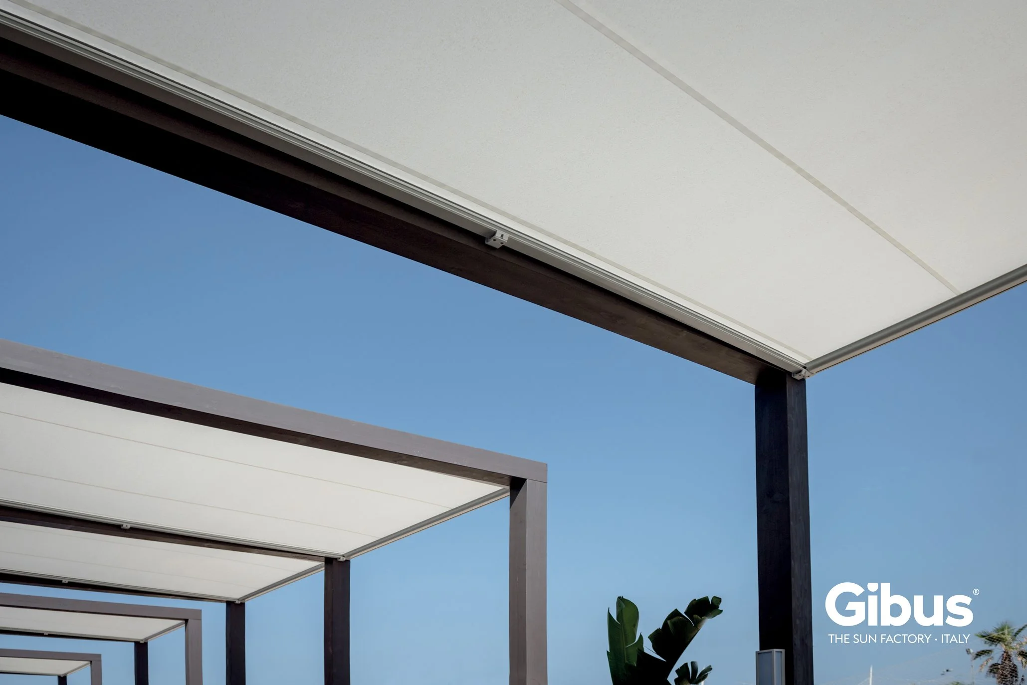 Modern pergolas with white canopies and dark structural supports against a blue sky.