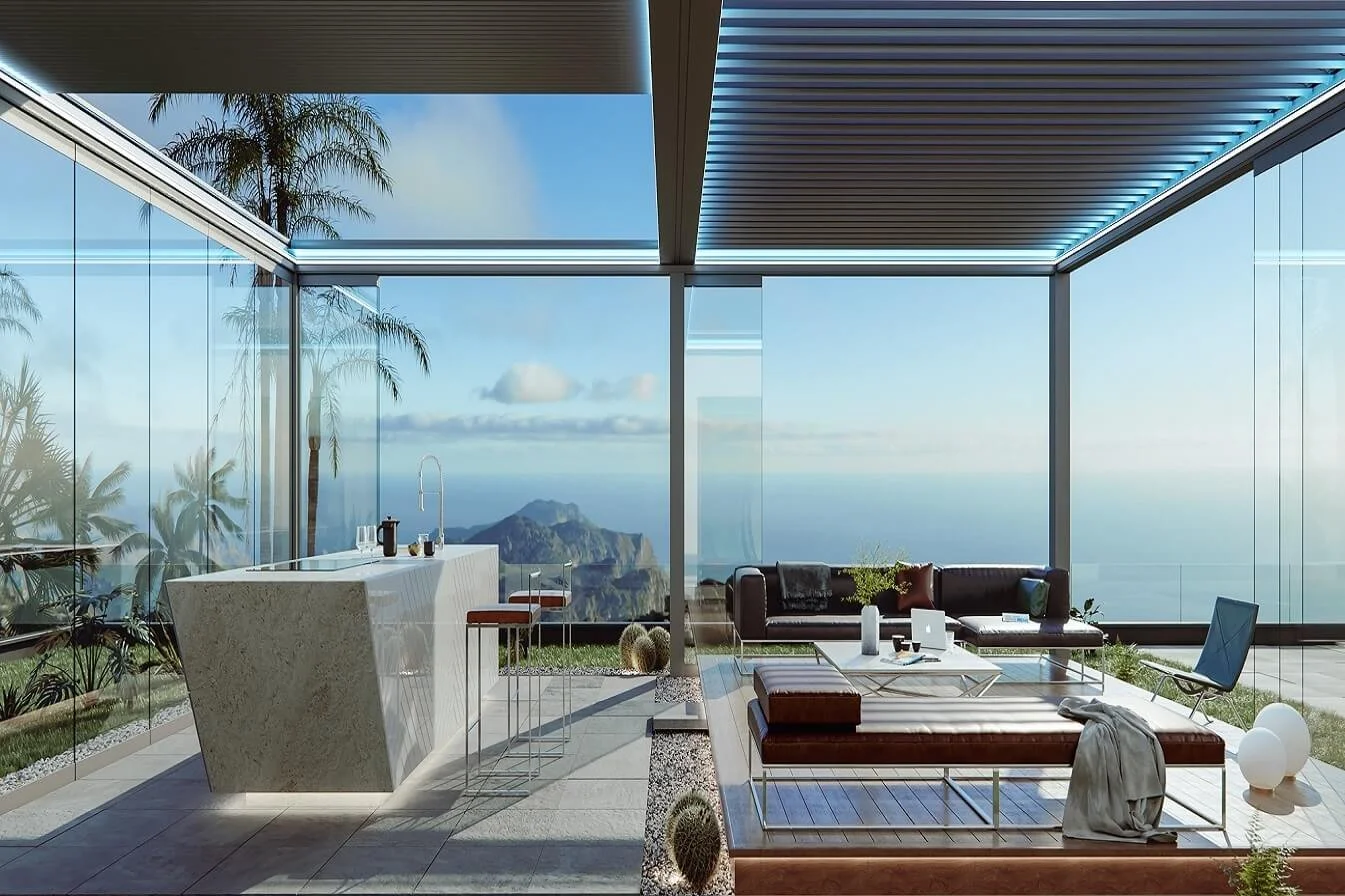 Modern living room with floor-to-ceiling glass walls offering a view of mountains and ocean, containing a kitchen island, a leather sofa, a coffee table, a lounge chair, and decorative objects.