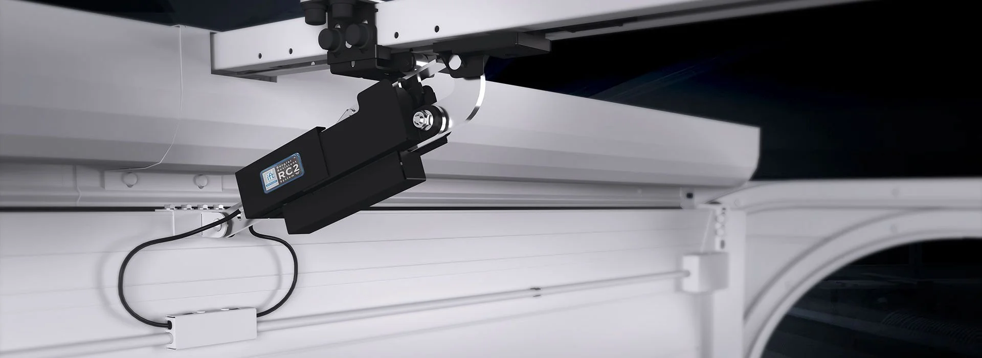 Close-up of mechanical and electronic components inside a washing machine, showing a black motor labeled RC2, wiring, and internal metal parts.