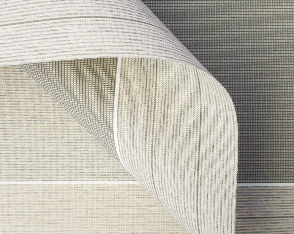 Close-up of fabric with horizontal and vertical striped patterns in shades of white, beige, and gray.