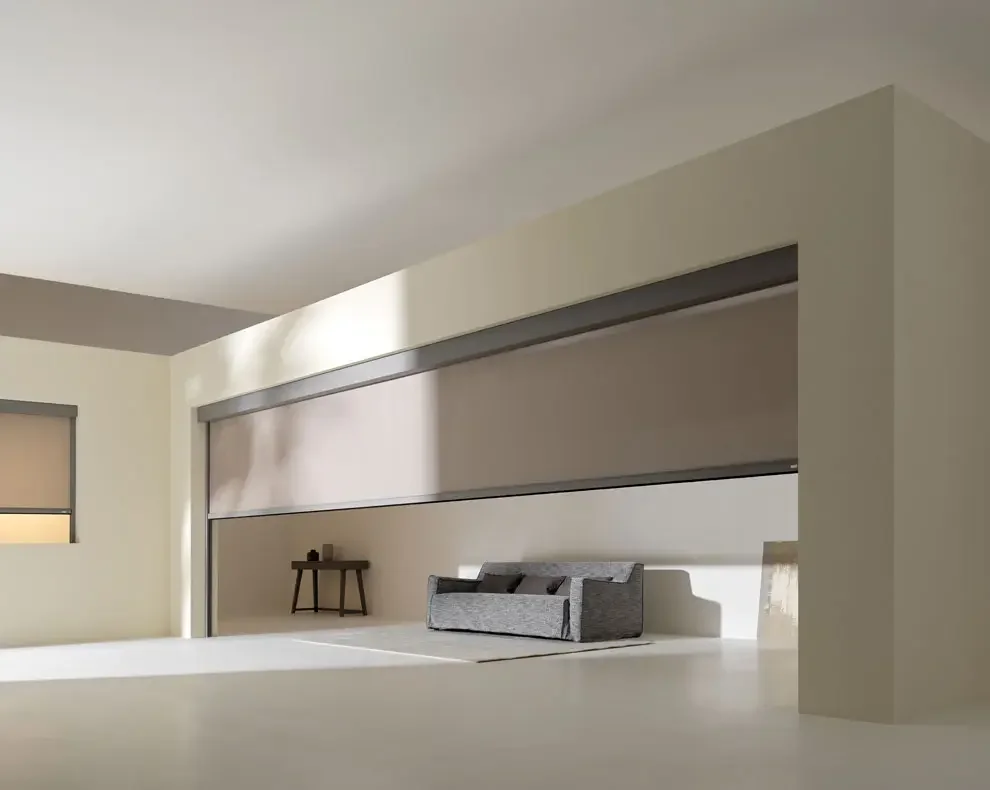 Minimalist living room with a gray sofa, a small wooden side table, and closed window blinds, with soft natural lighting.