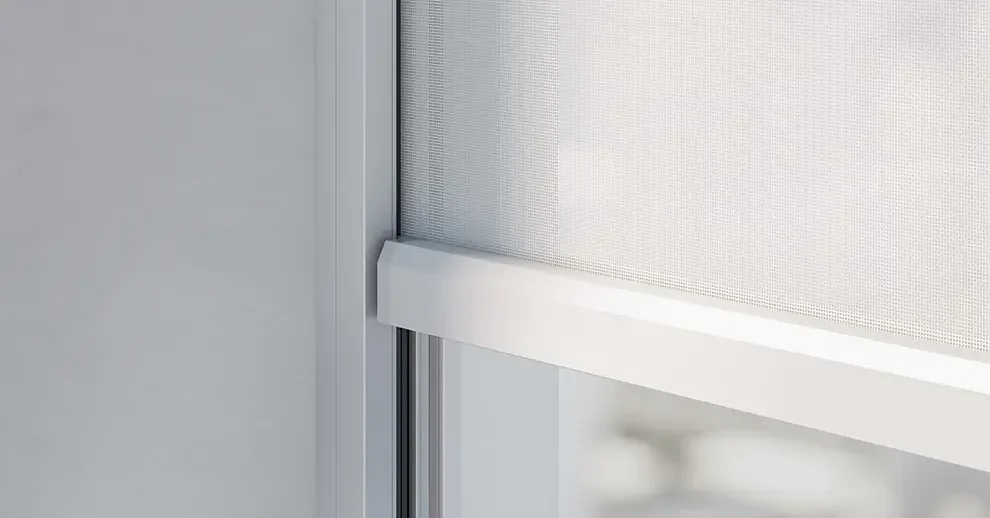 Close-up of a window with a light-colored frame and a white screen or shade partially rolled down.