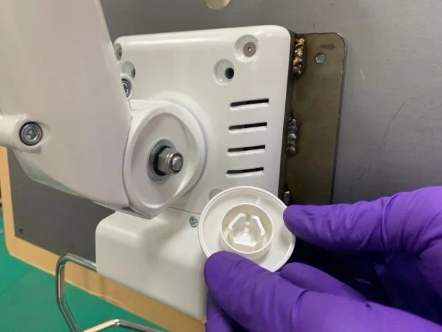 Main en main portant un gant violet insérant une pièce de pièce de machinerie mécanique.