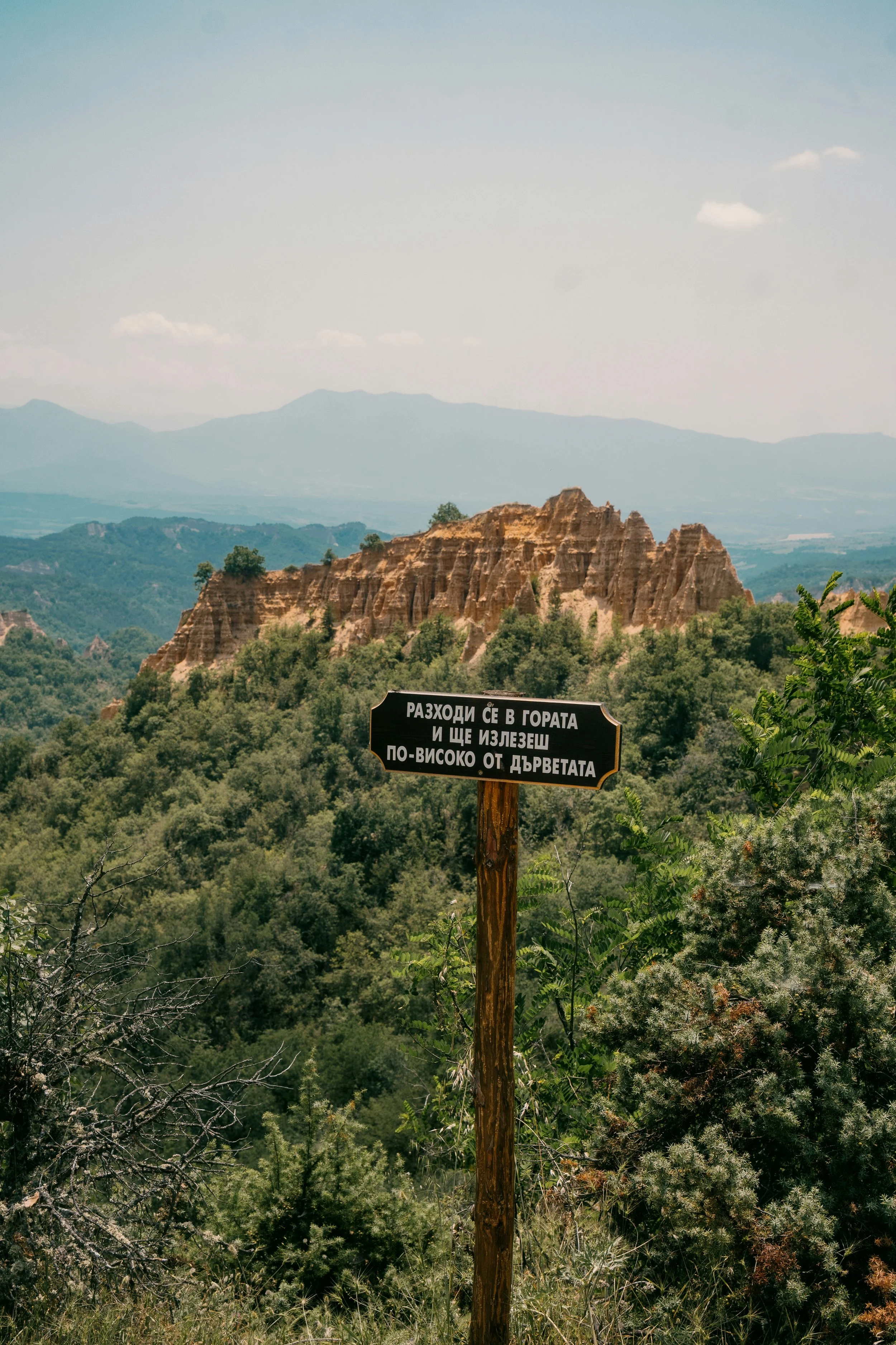 Paysage de montagnes bulgares avec un panonceau en bulgare et un relief rocheux au centre.