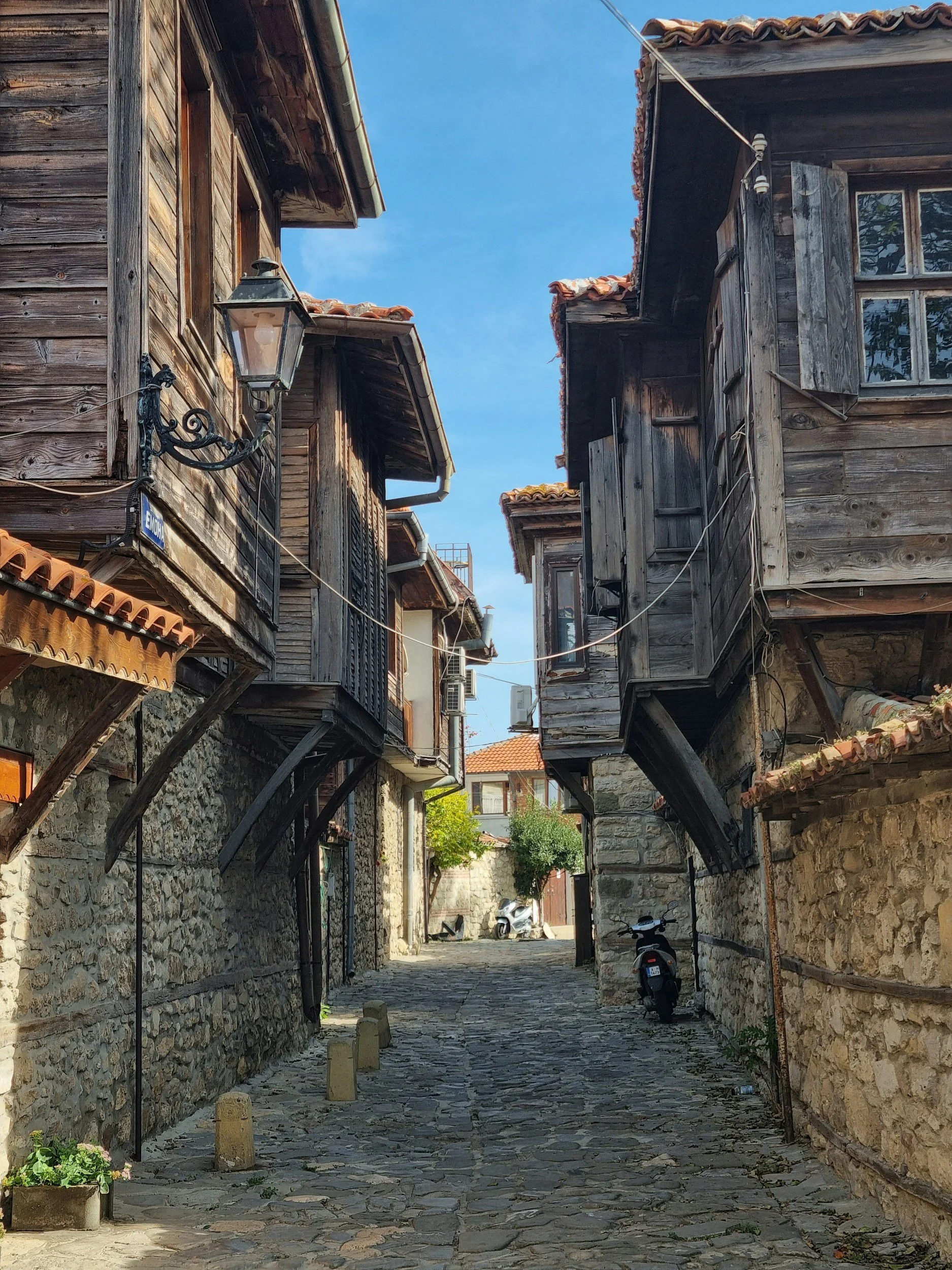 Ruelle pavée d’un village bulgare traditionnel, maisons en bois et pierre, immersion culturelle authentique