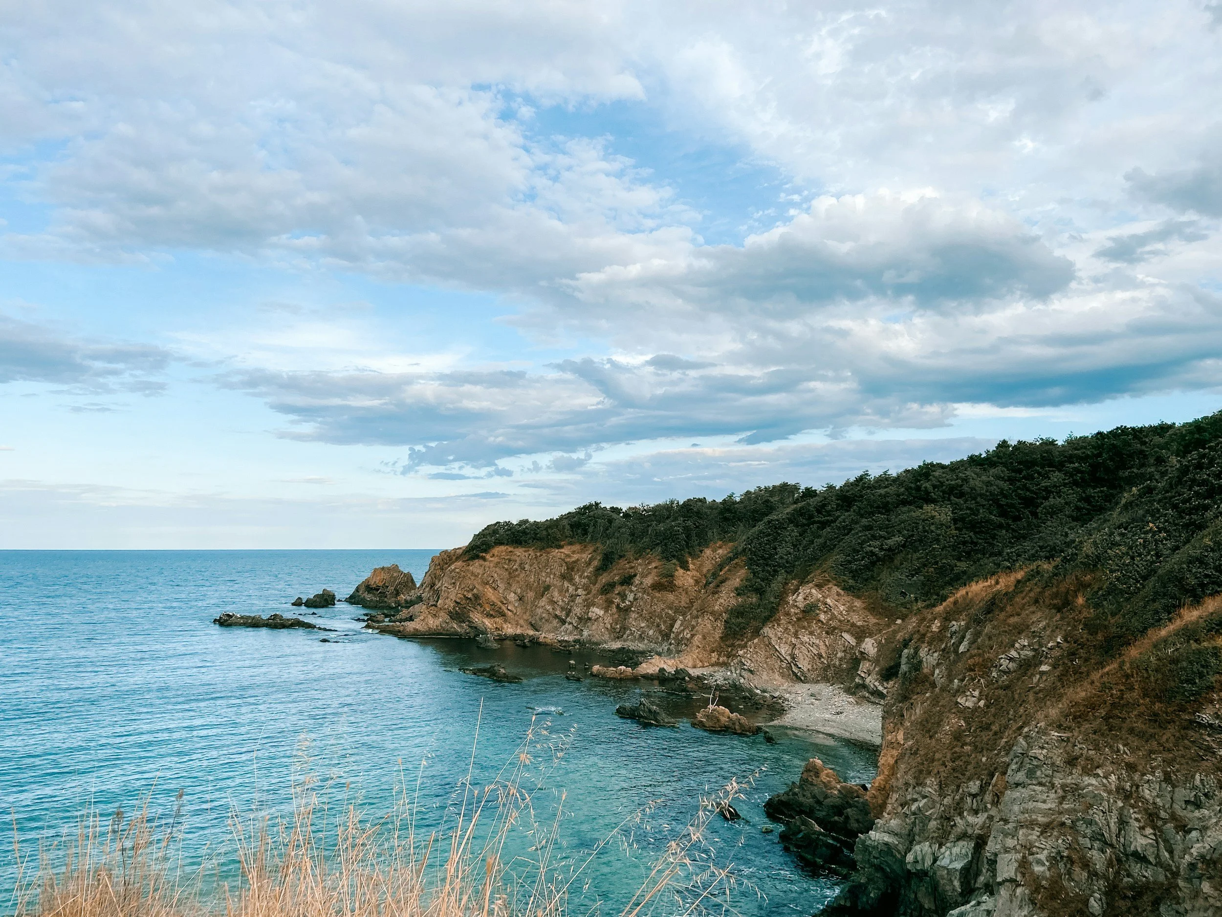 Côte rocheuse avec des falaises et la mer calme sous un ciel partiellement nuageux en Bulgarie.