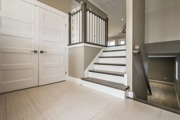 Interior view of a modern home with white stairs, a carpeted landing, and white paneled closet doors.