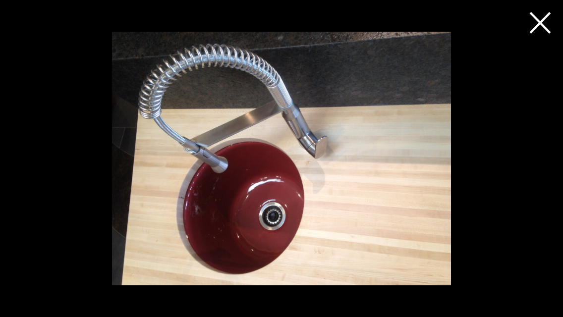 Red circular kitchen sink with a flexible metallic faucet on a wooden countertop.