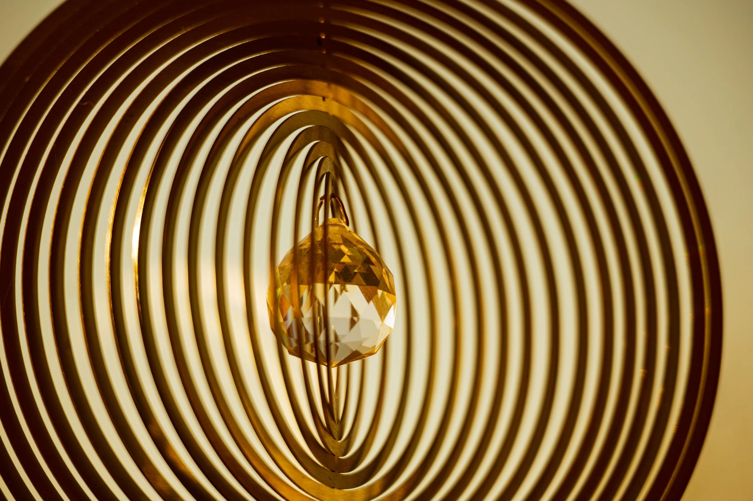 Nahaufnahme einer Lampe mit goldnem Kristall, umgeben von konzentrischen goldenen Ringen