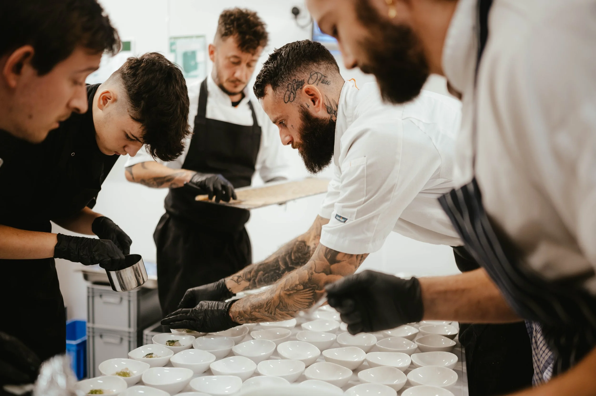Chefs preparing and plating dishes in a professional kitchen.