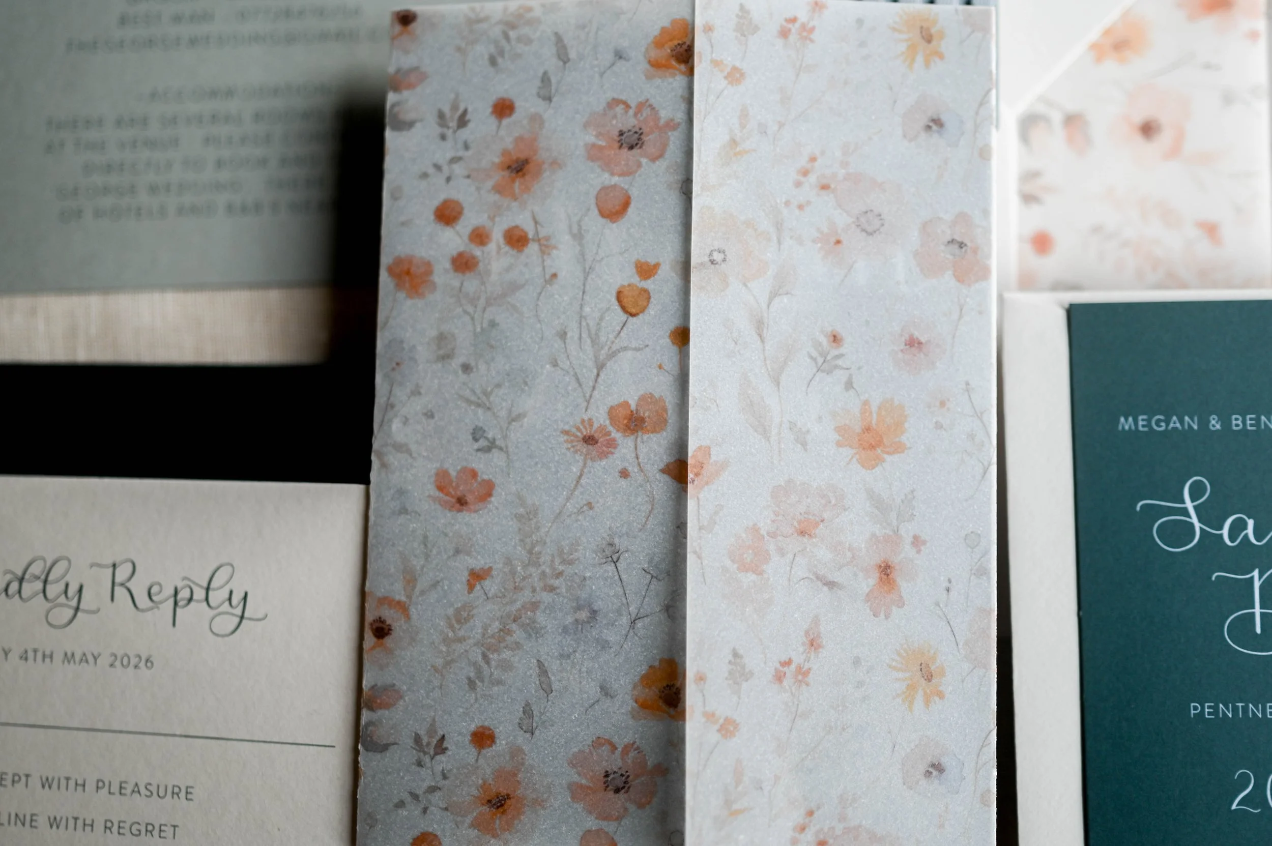 Close-up of wedding invitation cards with floral patterns and elegant fonts.