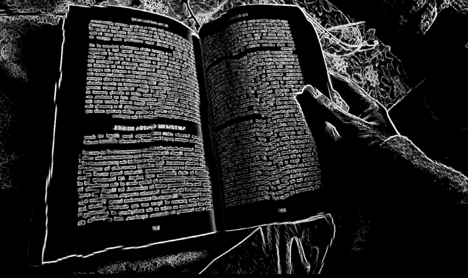 A person reading a large open book with dense text, captured in a black-and-white, high-contrast style.