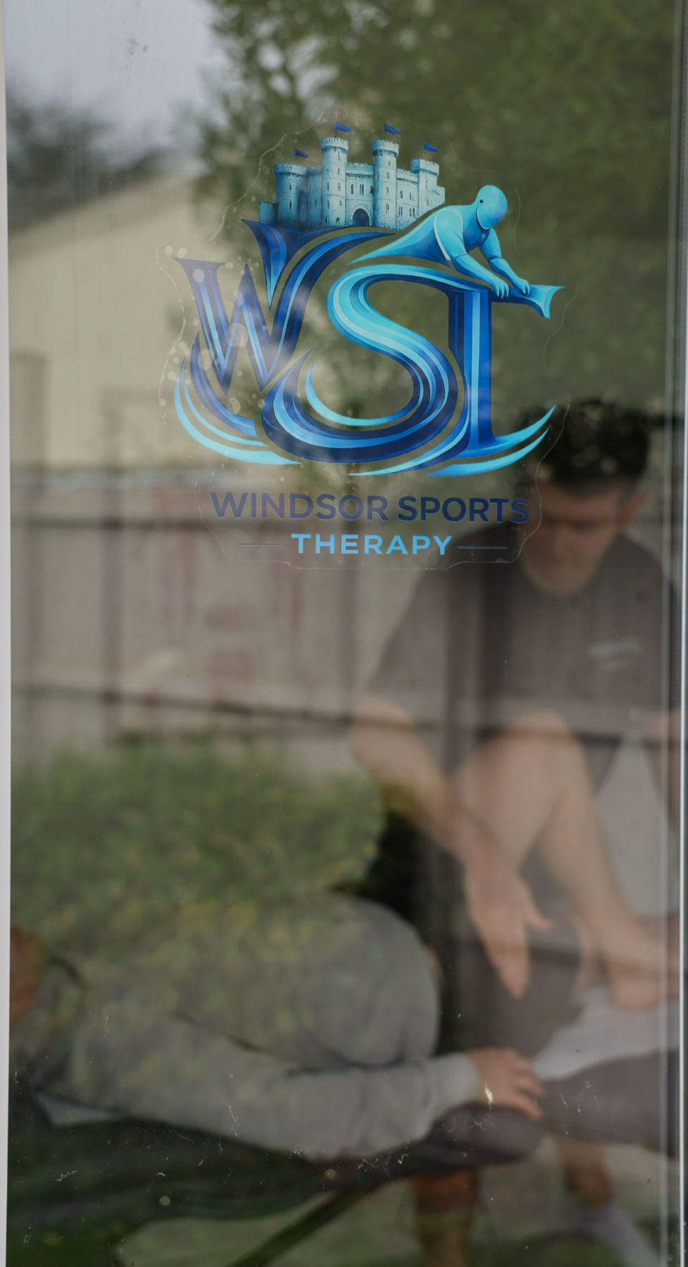 Window sticker of Windsor Sports Therapy with a blue castle and the words "Windsor Sports Therapy" in blue