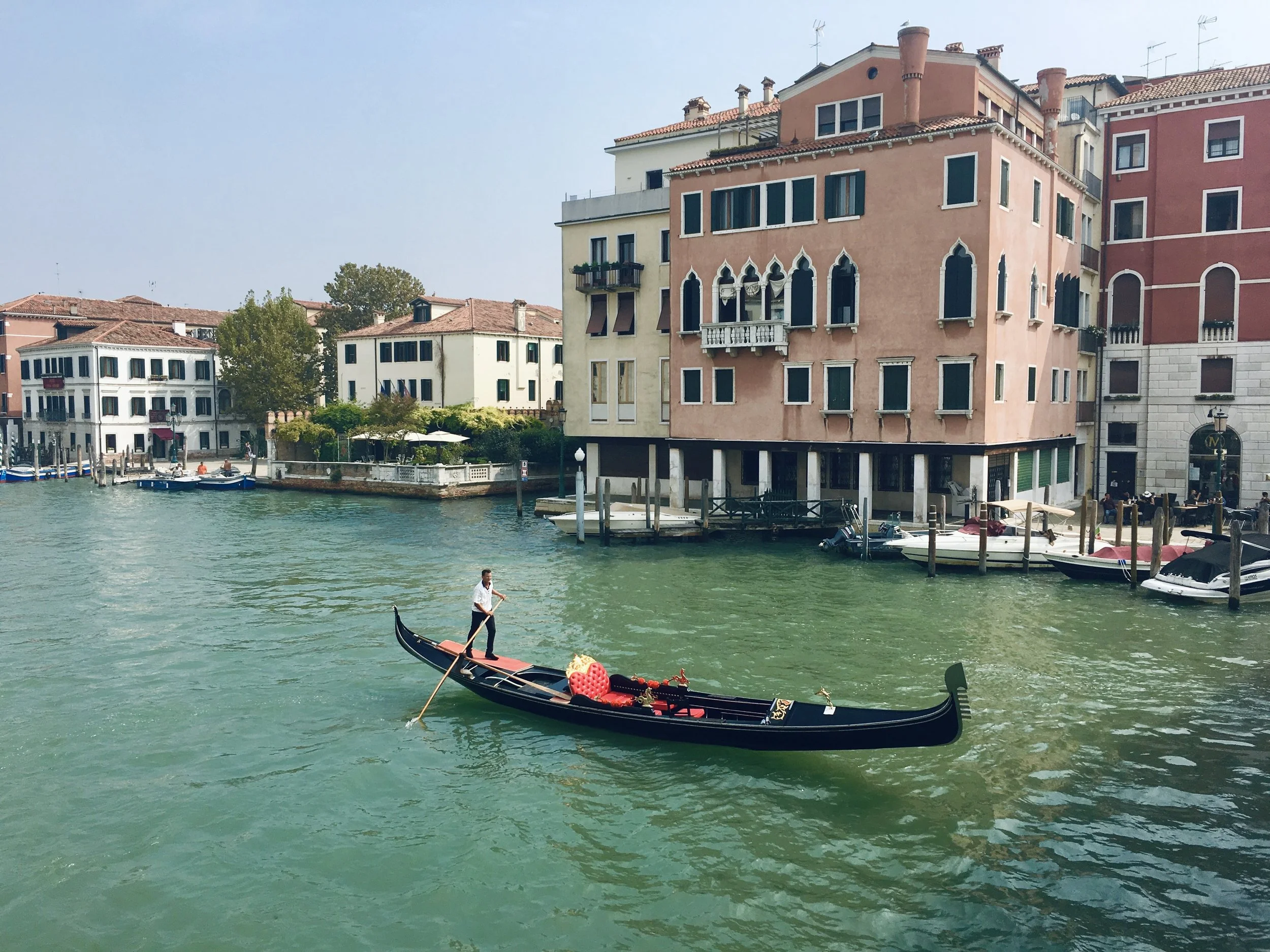 Gondola on a canal in Venice, Italy, with colorful buildings and boats along the waterfront.