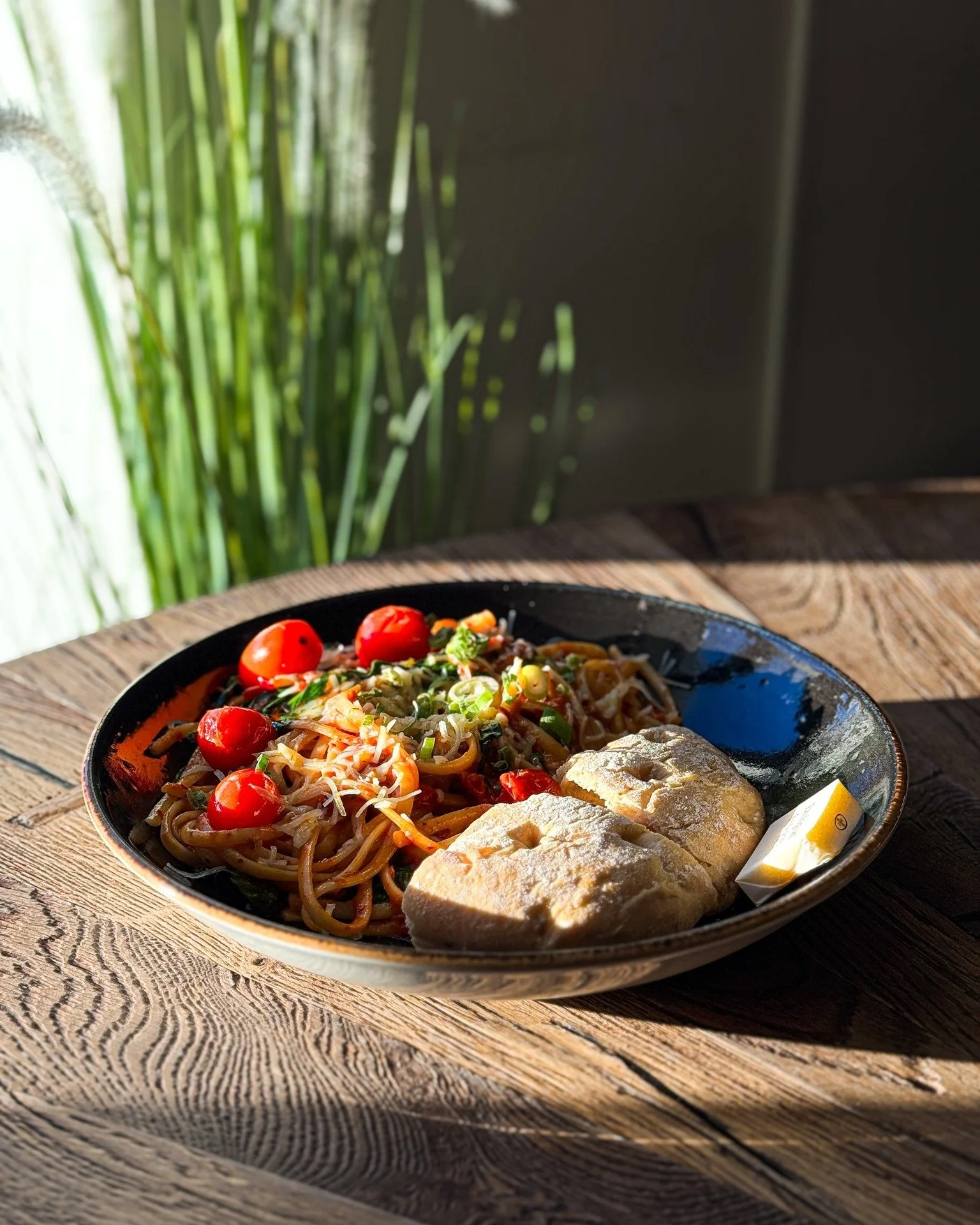 Pasta med cherrytomater og grønnsaker, og to brødskiver med smør.
