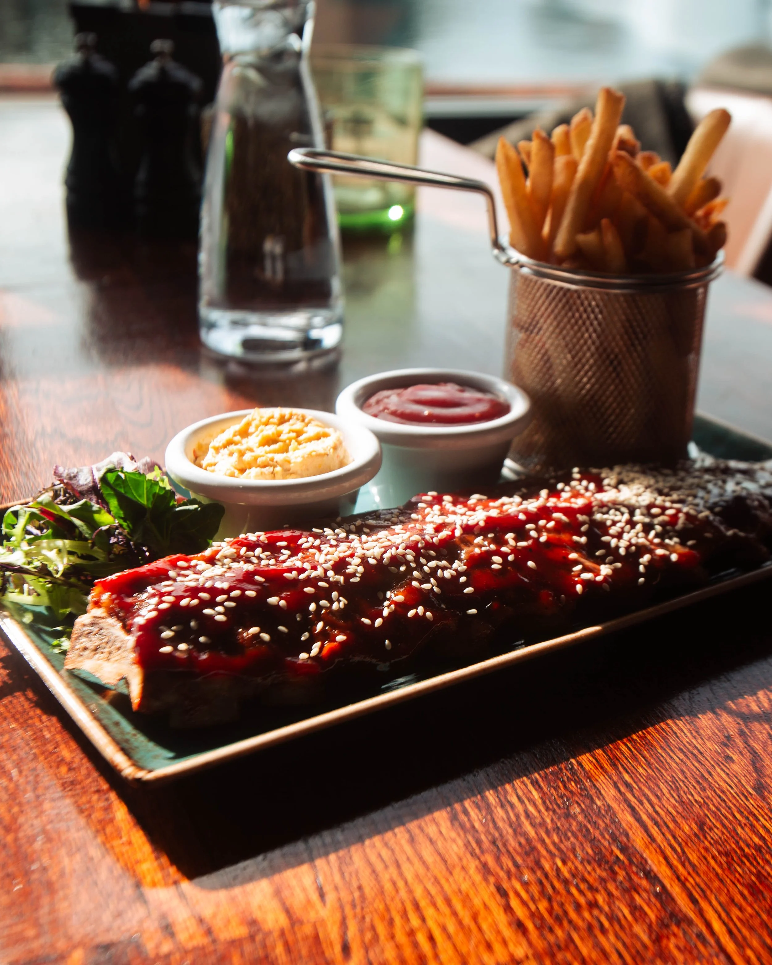 En tallerken med biff med saus og sesamfrø, sider av salat,.