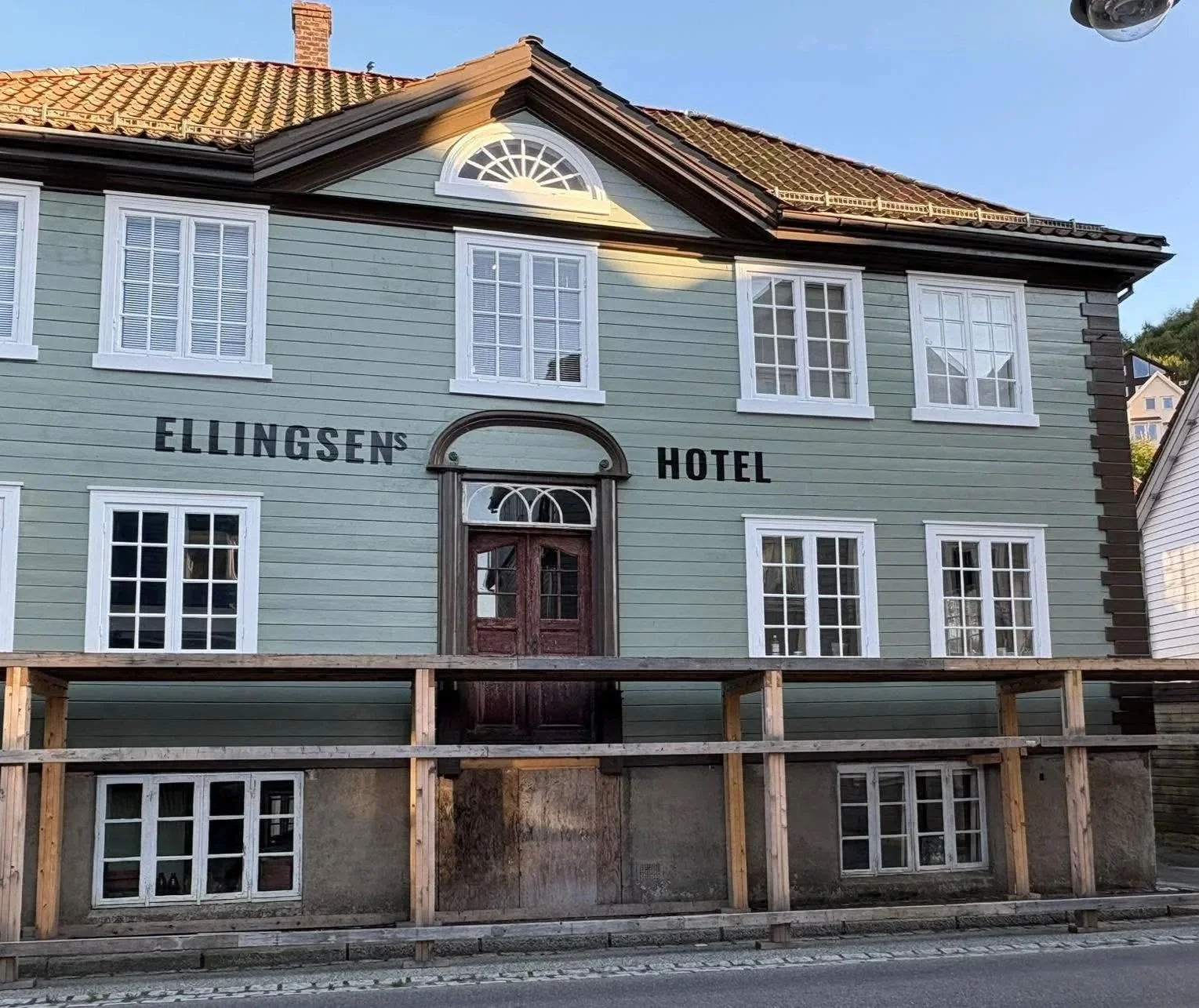 Ellingsens Hotel, en treetasjes gammel hotellbygning under restaurering, malt i mintgrønn farge med hvite vindusrammer og mørkebrunt frontdør.