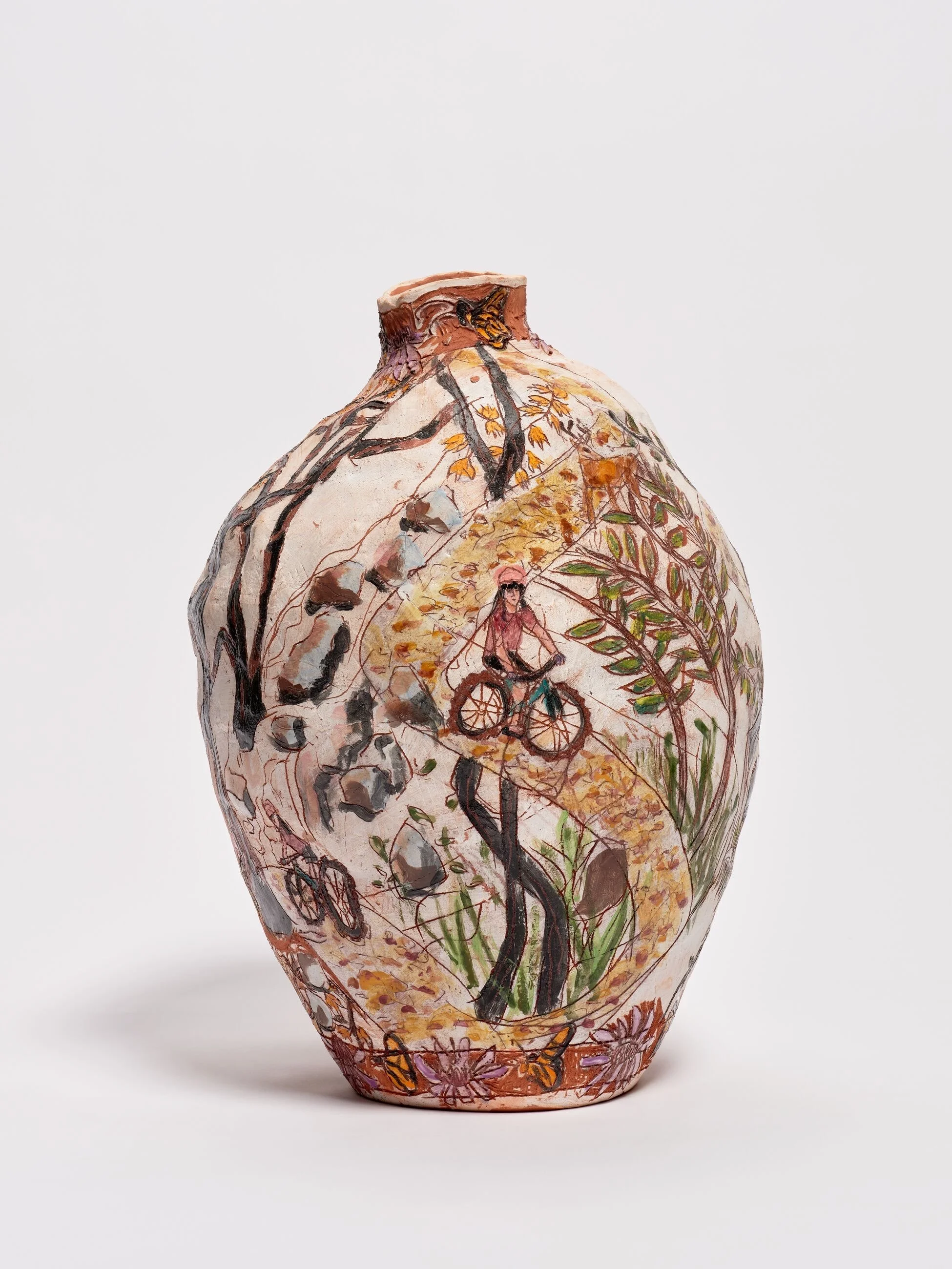 Decorative ceramic vase with a painted outdoor scene featuring a cyclist on a winding path surrounded by trees and rocks.