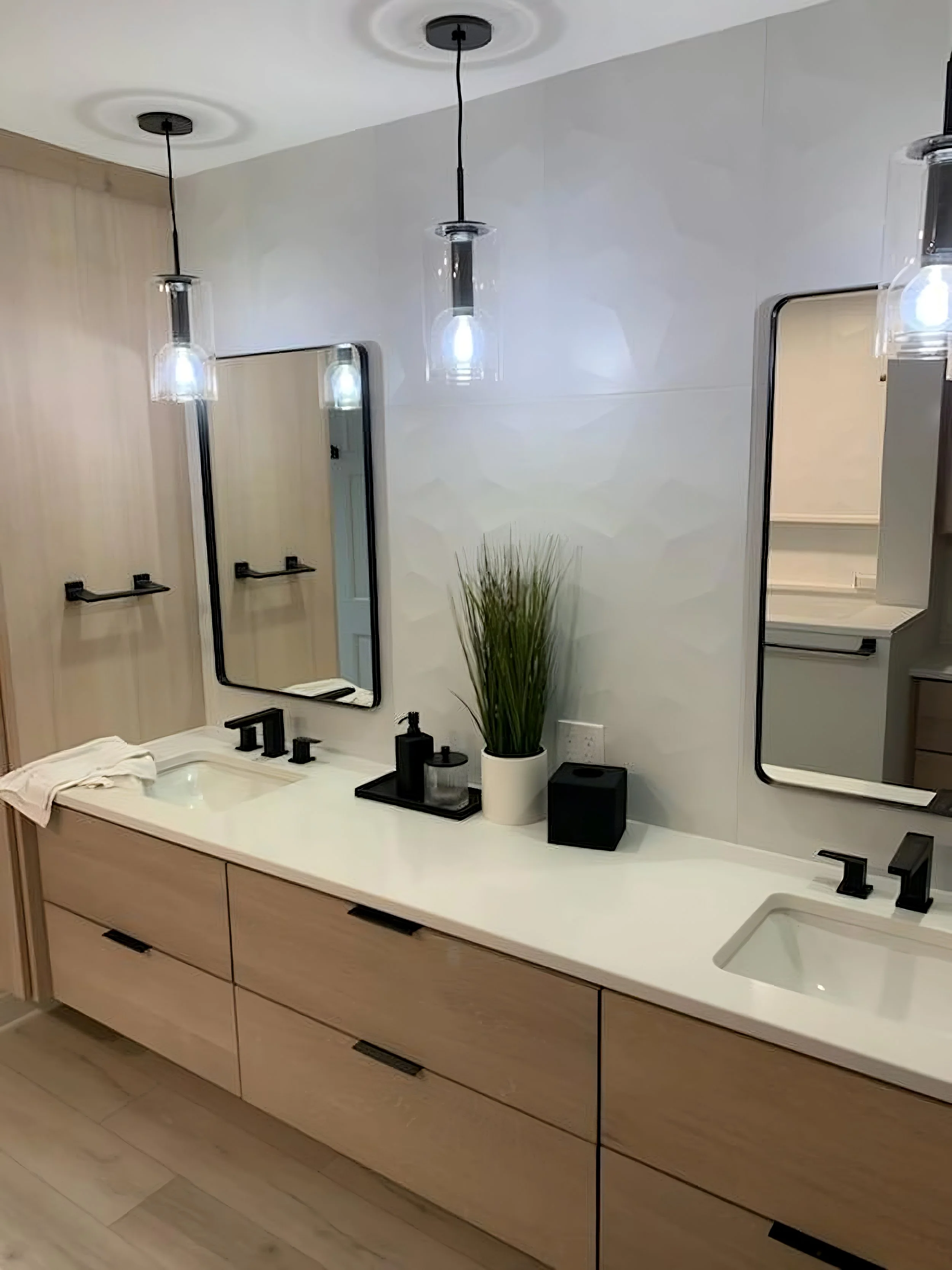 Modern bathroom vanity with a double sink, two black-framed mirrors, black fixtures, and decorative plants.