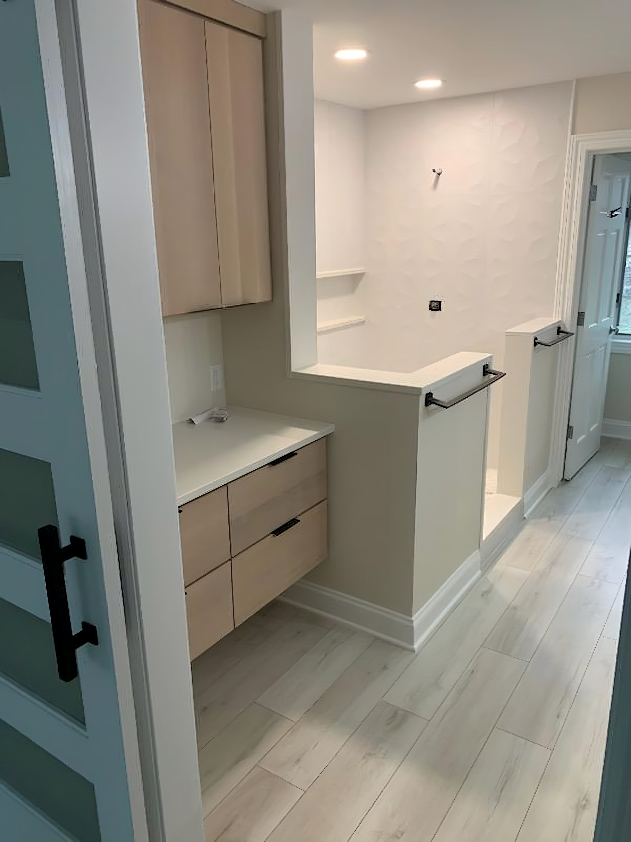 Empty kitchen or laundry room with light wood cabinets, white countertops, and light-colored tiled flooring. The space is well-lit with ceiling lights.