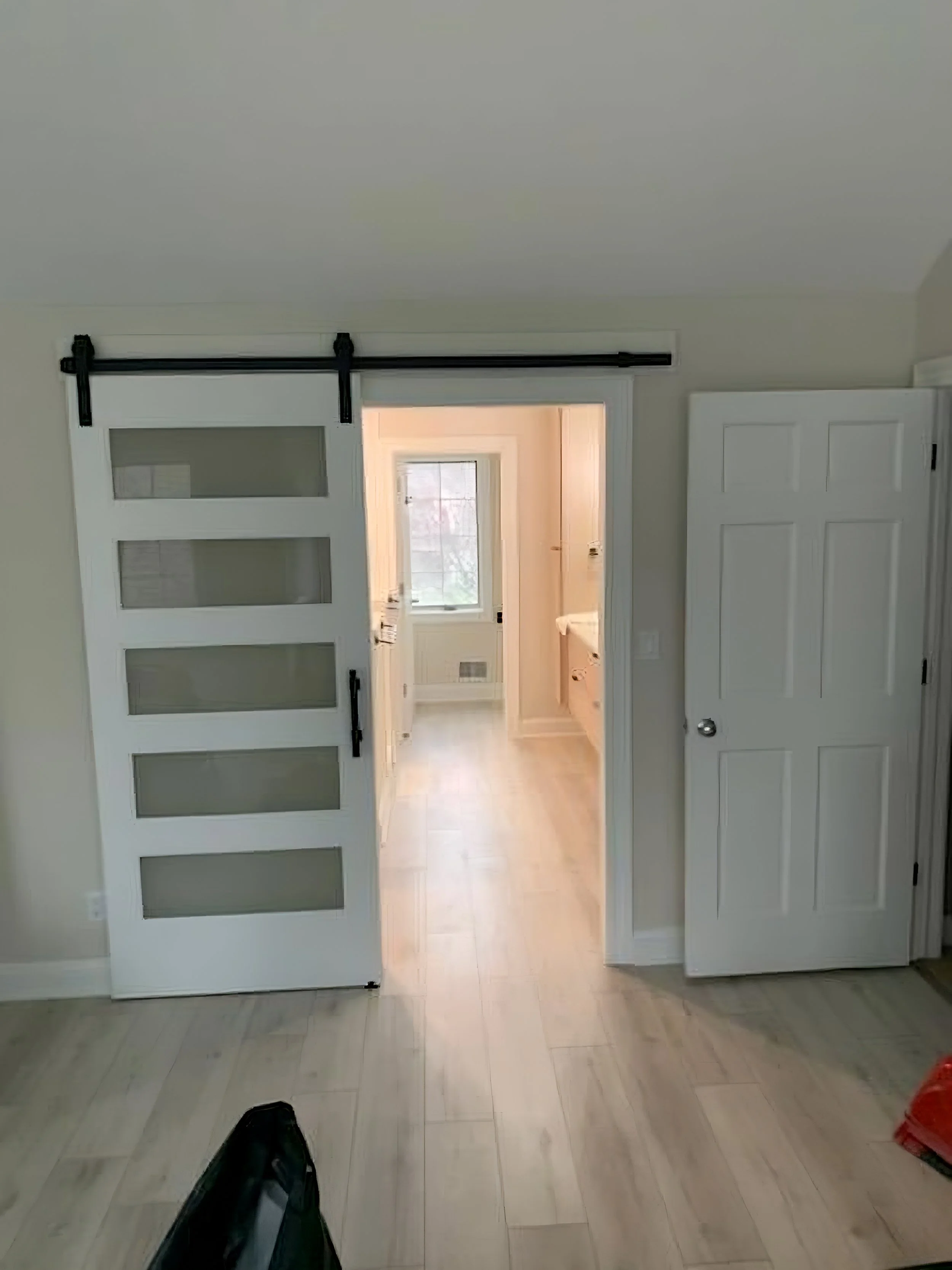 View of a room opening into a bathroom with sliding barn door and traditional door.