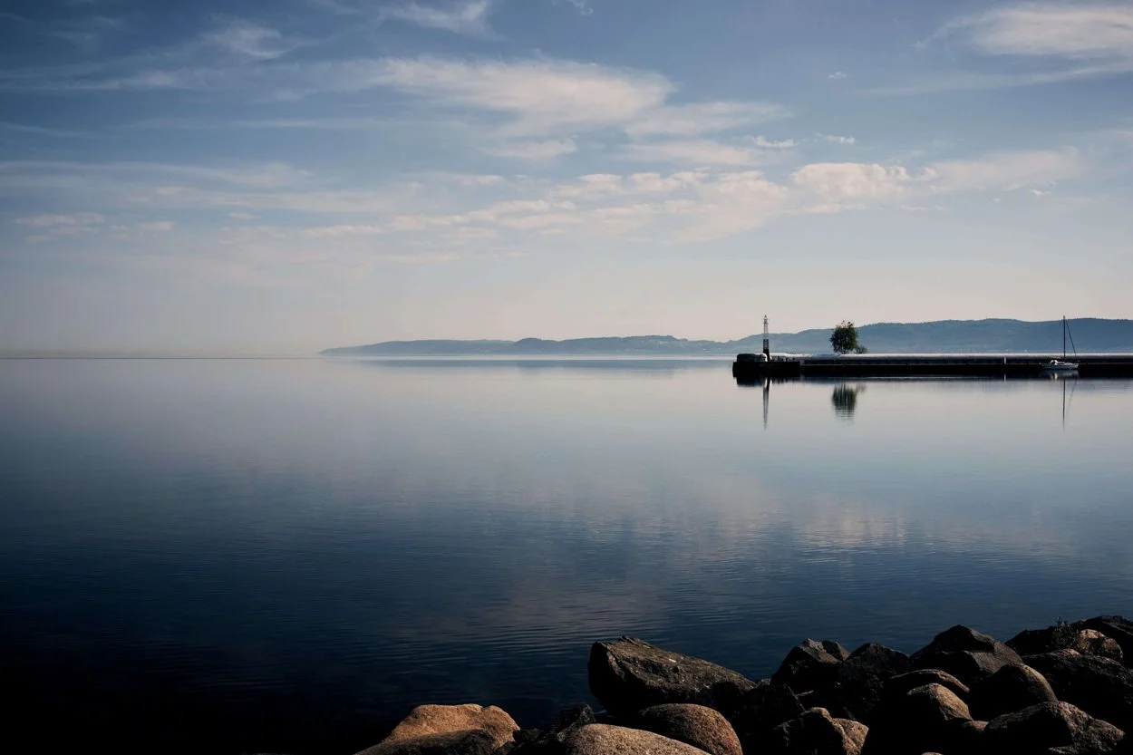 serene scene of a lake with a lighthouse in the distance