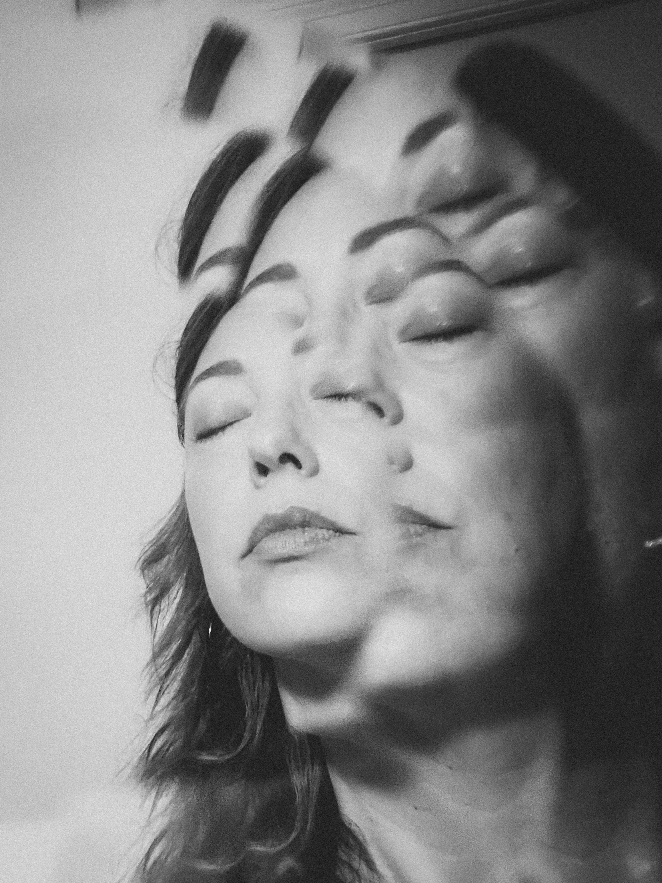 Black and white photo of a woman’s face with her eyes closed, multiple overlapping images creating a surreal, layered effect.